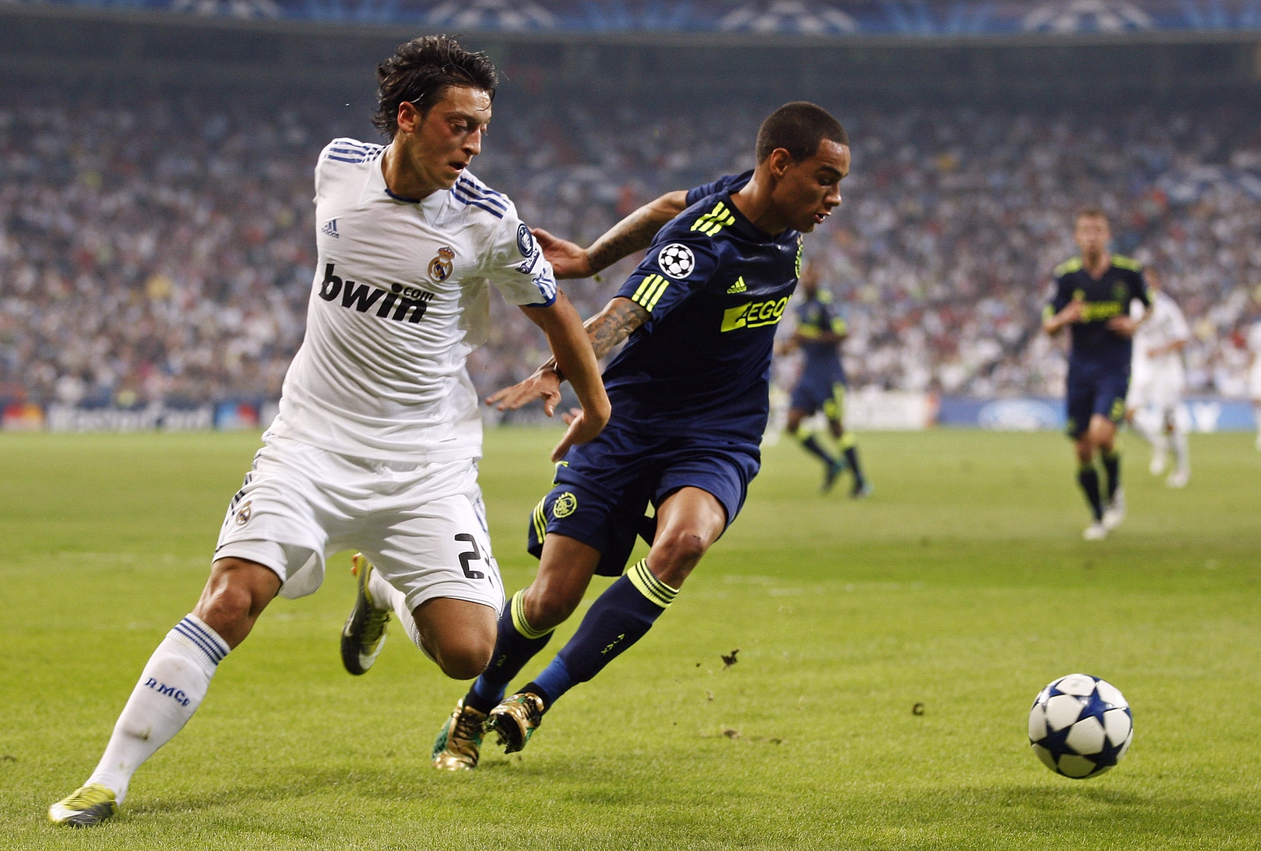 MADRID, SPAIN - SEPTEMBER 15: Mesut Ozil of Real Madrid fights for the ball with Gregory van der Wiel of Ajax during the UEFA Champions League group G match between Real Madrid and AFC Ajax at Estadio Santiago Bernabeu on September 15, 2010 in Madrid, Spa