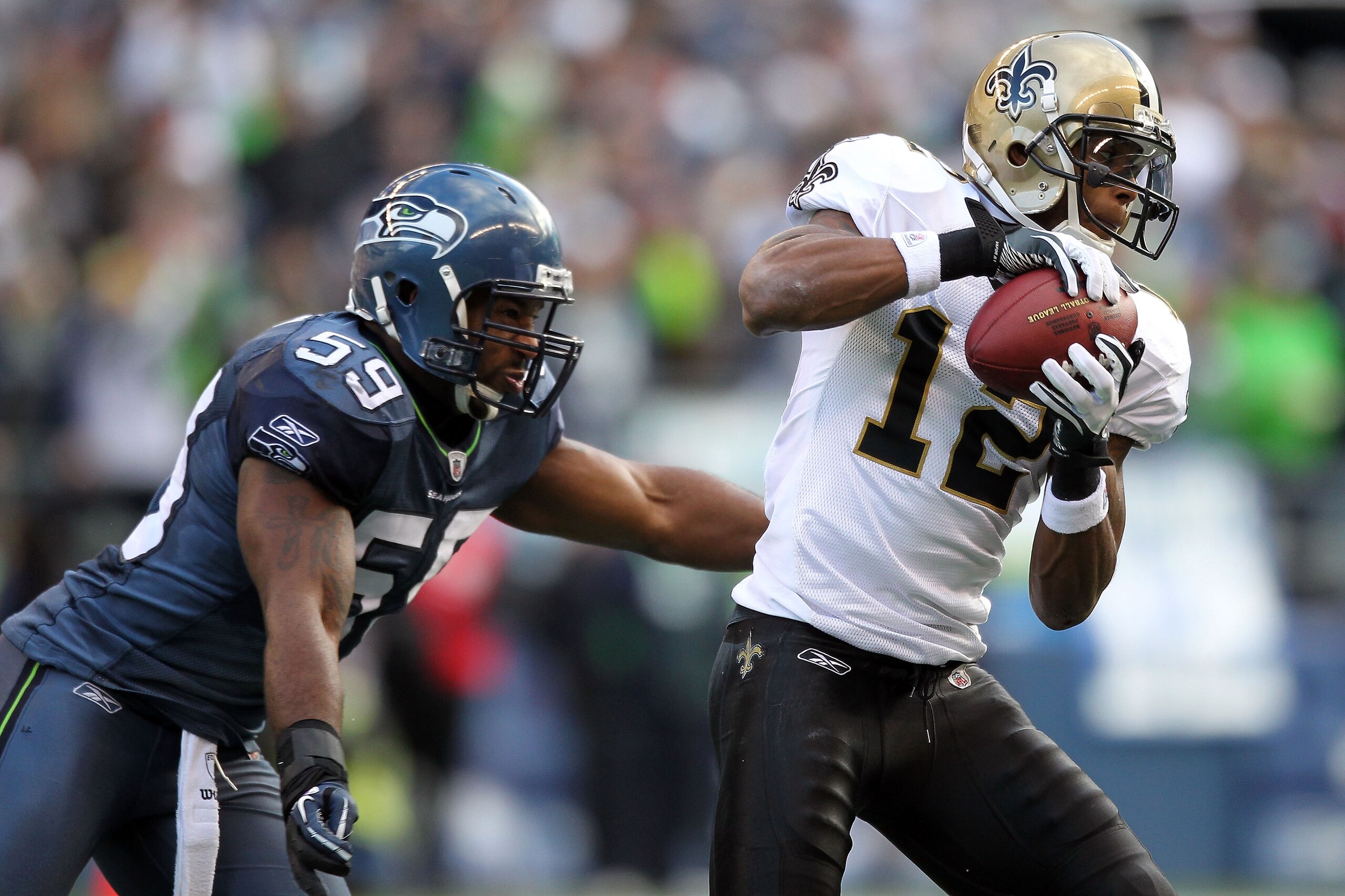SEATTLE, WA - JANUARY 08:  Marques Colston #12 of the New Orleans Saints catches the ball against Aaron Curry #59 of the Seattle Seahawks in the first half during the 2011 NFC wild-card playoff game at Qwest Field on January 8, 2011 in Seattle, Washington