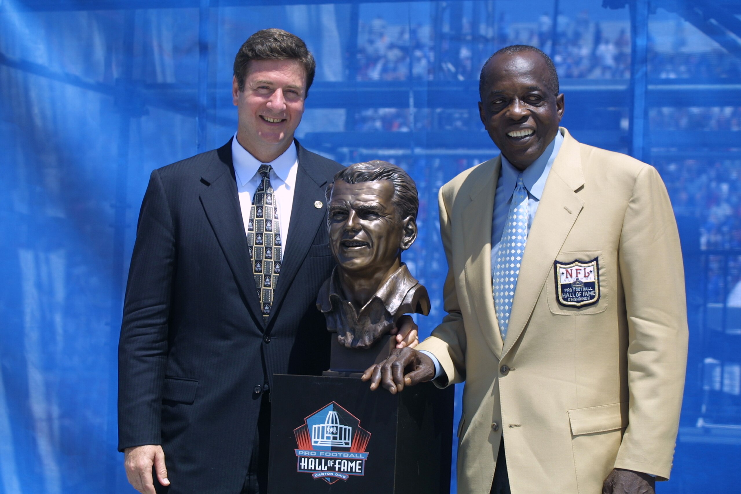 CANTON, OHIO - AUGUST 3:  Virginia Senator George Allen (left) stands next to a bust in the likeness of his father, Coach George Allen with his presenter Deacon Jones after Coach Allen's induction into the National Football League Hall of Fame on August 3