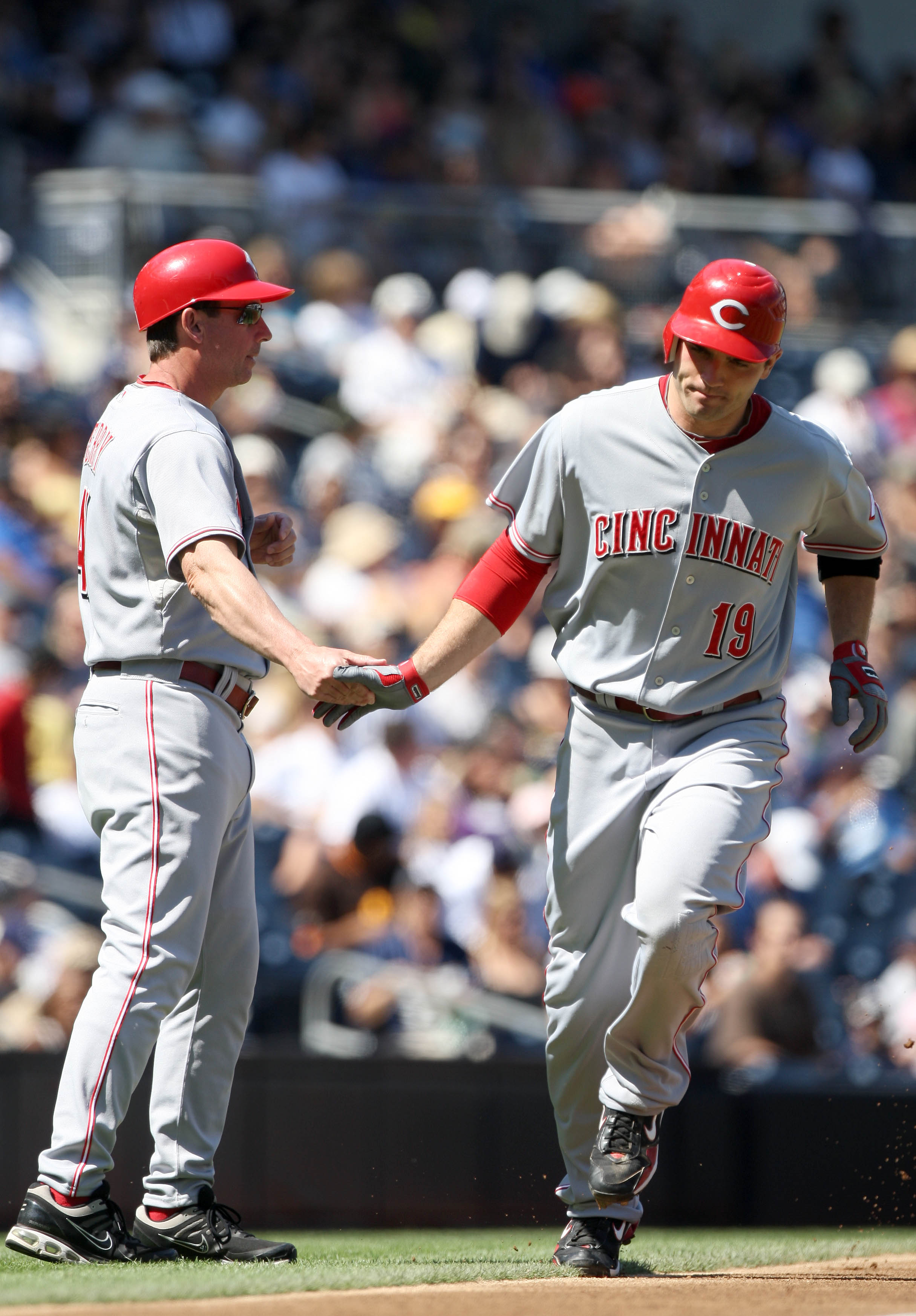 SAN DIEGO, CA - SEPTEMBER 26:  Joey Votto #19 of Cincinnati Reds is greeted by third base coach Mark Berry as he rounds the base after hitting a solo home run against the San Diego Padres during the first inning of their MLB game on September 26, 2010 at