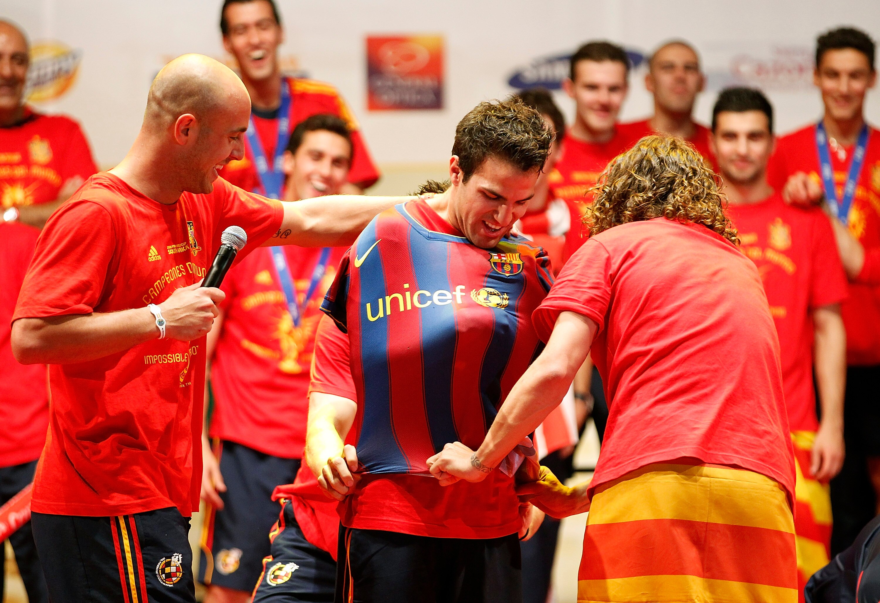 MADRID, SPAIN - JULY 12:  Pepe Reina and Carles Puyol of Spanish national football team put on a shirt of FC Barcelona to Cesc Fabregas during the Spanish team's victory parade following their victory over the Netherlands in the 2010 FIFA World Cup on Jul