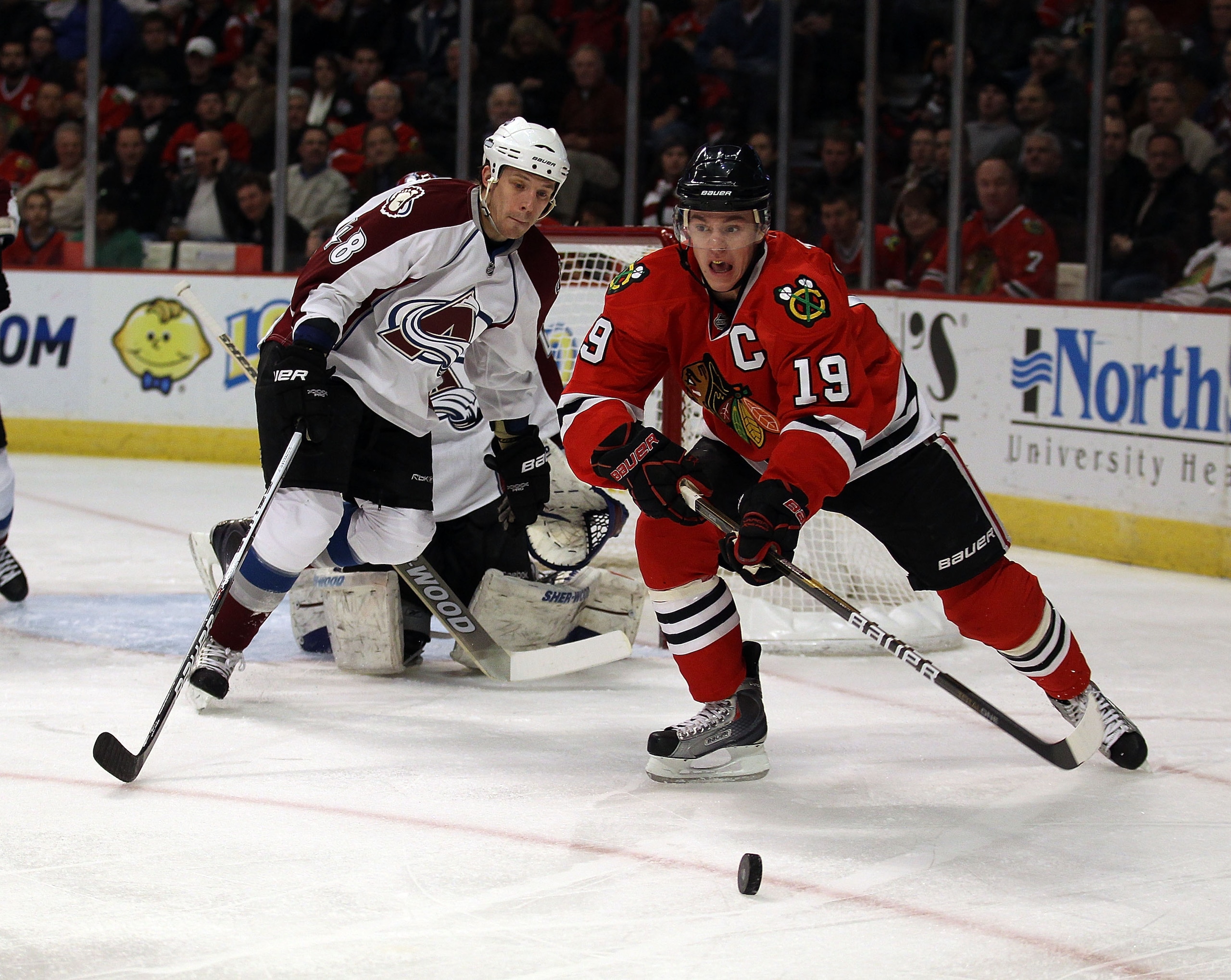 CHICAGO, IL - DECEMBER 15: Jonathan Toews #19 of the Chicago Blackhawks passes the puck in front of Matt Hunwick #48 of the Colorado Avalanche at the United Center on December 15, 2010 in Chicago, Illinois. The Avalanche defeated the Blackhawks 4-3.  (Pho