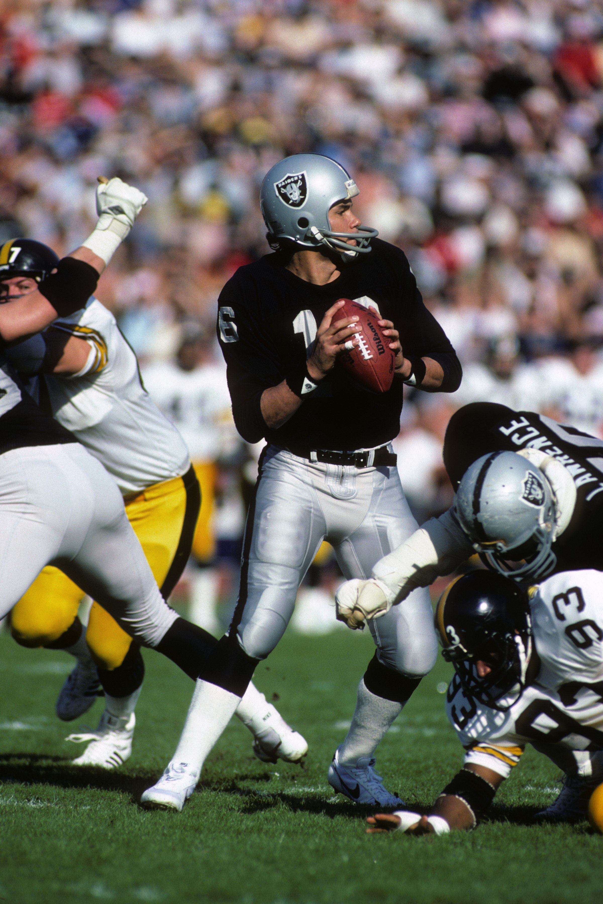 LOS ANGELES - JANUARY 1:  Quarterback Jim Plunkett #16 of the Los Angeles Raiders drops back to pass against Pittsburgh Steelers during the 1983 AFC Divisional Playoffs game at the Los Angeles Memorial Coliseum on January 1, 1984 in Los Angeles, Californi