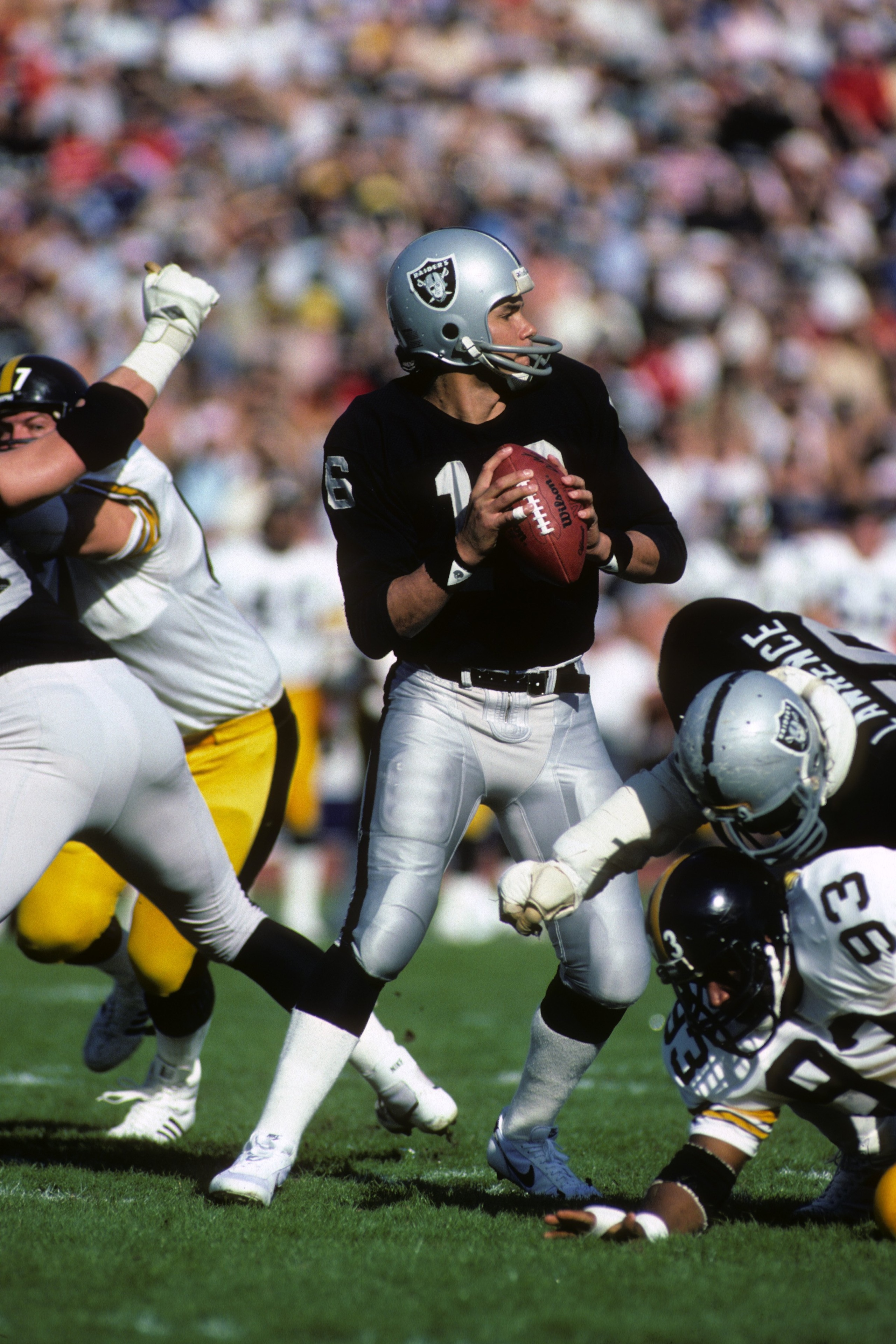 LOS ANGELES - JANUARY 1:  Quarterback Jim Plunkett #16 of the Los Angeles Raiders drops back to pass against Pittsburgh Steelers during the 1983 AFC Divisional Playoffs game at the Los Angeles Memorial Coliseum on January 1, 1984 in Los Angeles, Californi
