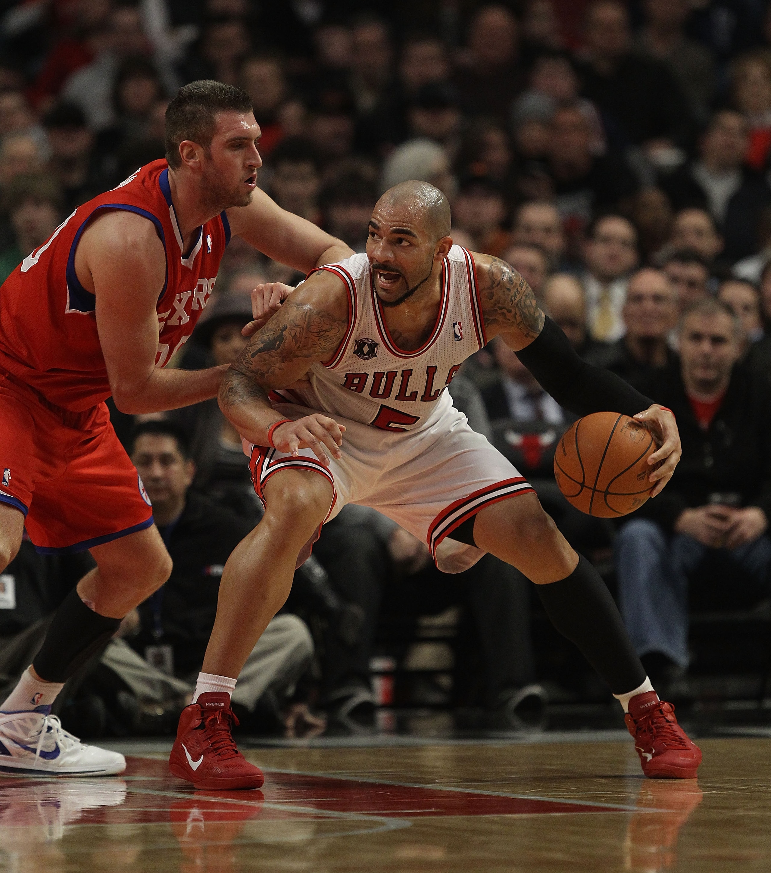 CHICAGO, IL - DECEMBER 21: Carlos Boozer #5 of the Chicago Bulls moves against Spencer Hawes #00 of the Philadelphia 76ers at the United Center on December 21, 2010 in Chicago, Illinois. The Bulls defeated the 76ers 121-76. NOTE TO USER: User expressly ac CHICAGO, IL - DECEMBER 21: Carlos Boozer #5 of the Chicago Bulls moves against Spencer Hawes #00 of the Philadelphia 76ers at the United Center on December 21, 2010 in Chicago, Illinois. The Bulls defeated the 76ers 121-76. NOTE TO USER: User expressly ac