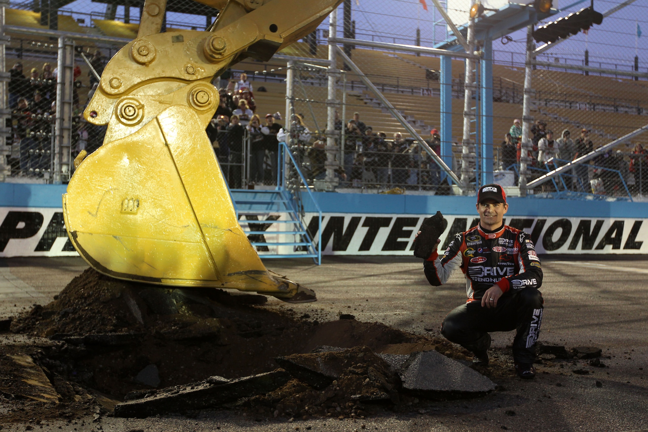 AVONDALE, AZ - FEBRUARY 27:  Jeff Gordon, driver of the #24 Drive to End Hunger Chevrolet, poses with a piece of the track after using an excavator to tear up the race track, following his win in the NASCAR Sprint Cup Series Subway Fresh Fit 500 at Phoeni