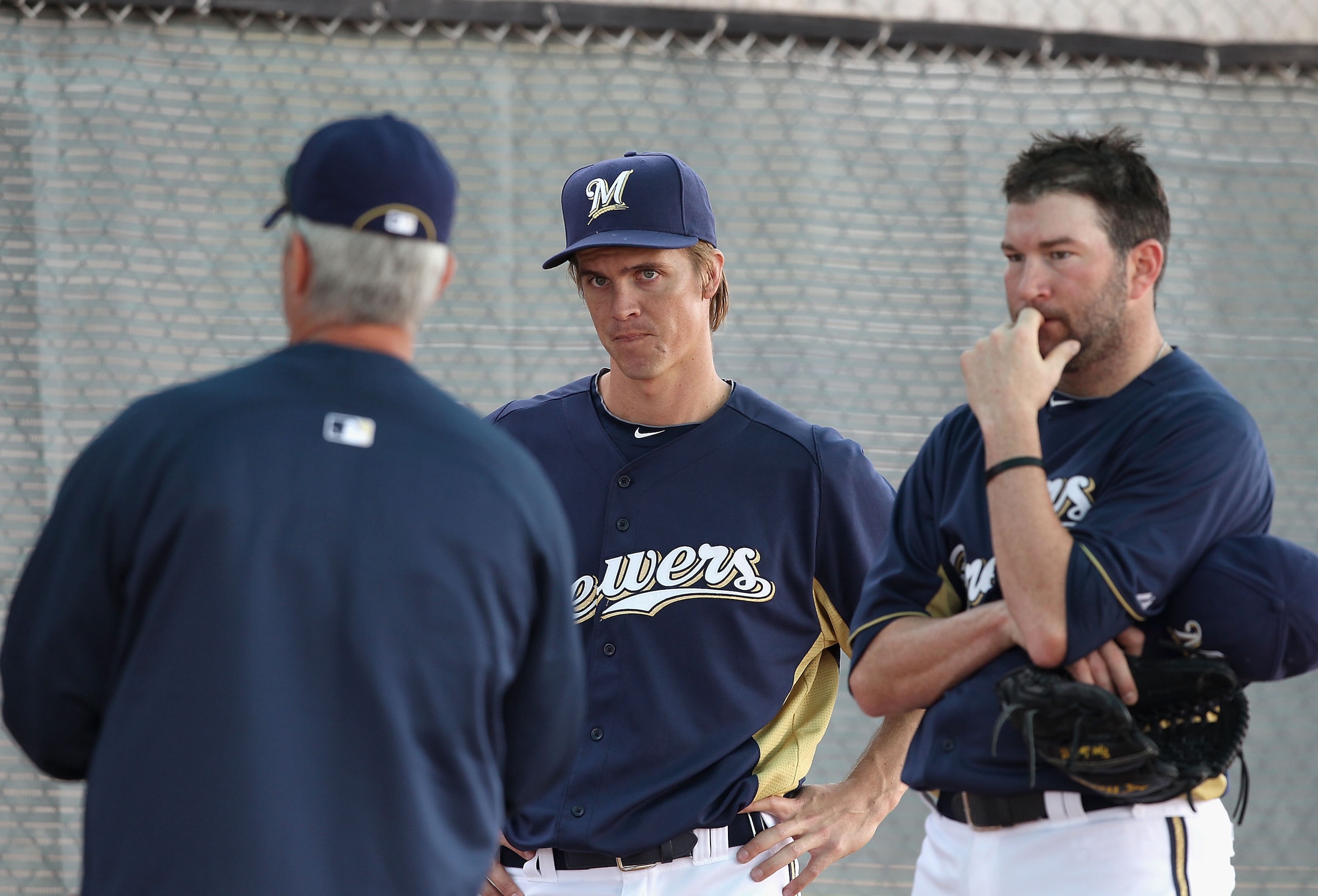 PHOENIX, AZ - FEBRUARY 18:  Pitchers Zack Greinke #13 (C) and Shaun Marcum #18 (R) of the Milwaukee Brewers listen to pitching coach Rick Kranitz (L) during a MLB spring training practice at Maryvale Baseball Park on February 18, 2011 in Phoenix, Arizona.
