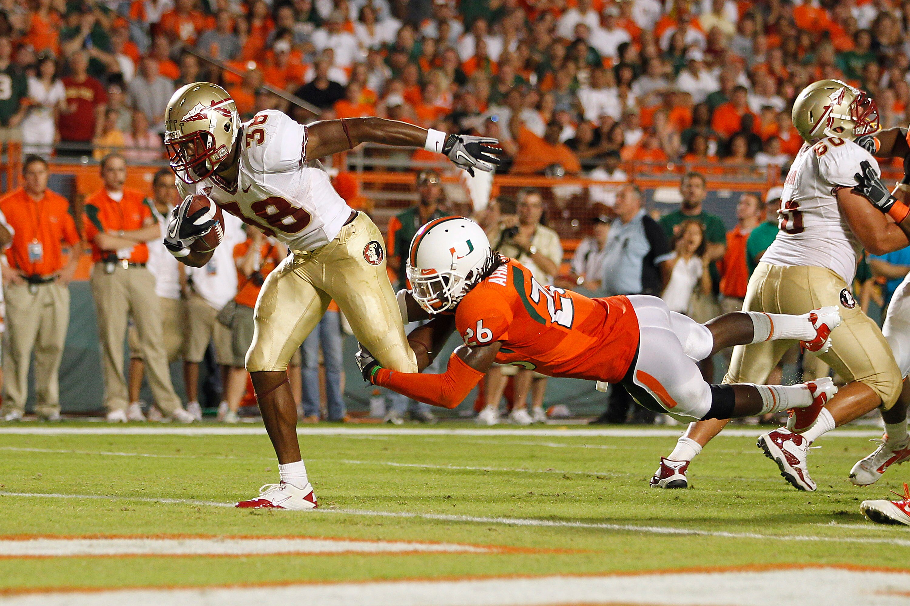MIAMI, FL - OCTOBER 9: Jermaine Thomas #38 of the Florida State Seminoles breaks the tackle of Ray-Ray Armstrong #26 of the Miami Hurricanes to score a touchdown in the second quarter on October 9, 2010 at Sun Life Stadium in Miami, Florida. (Photo by Joe