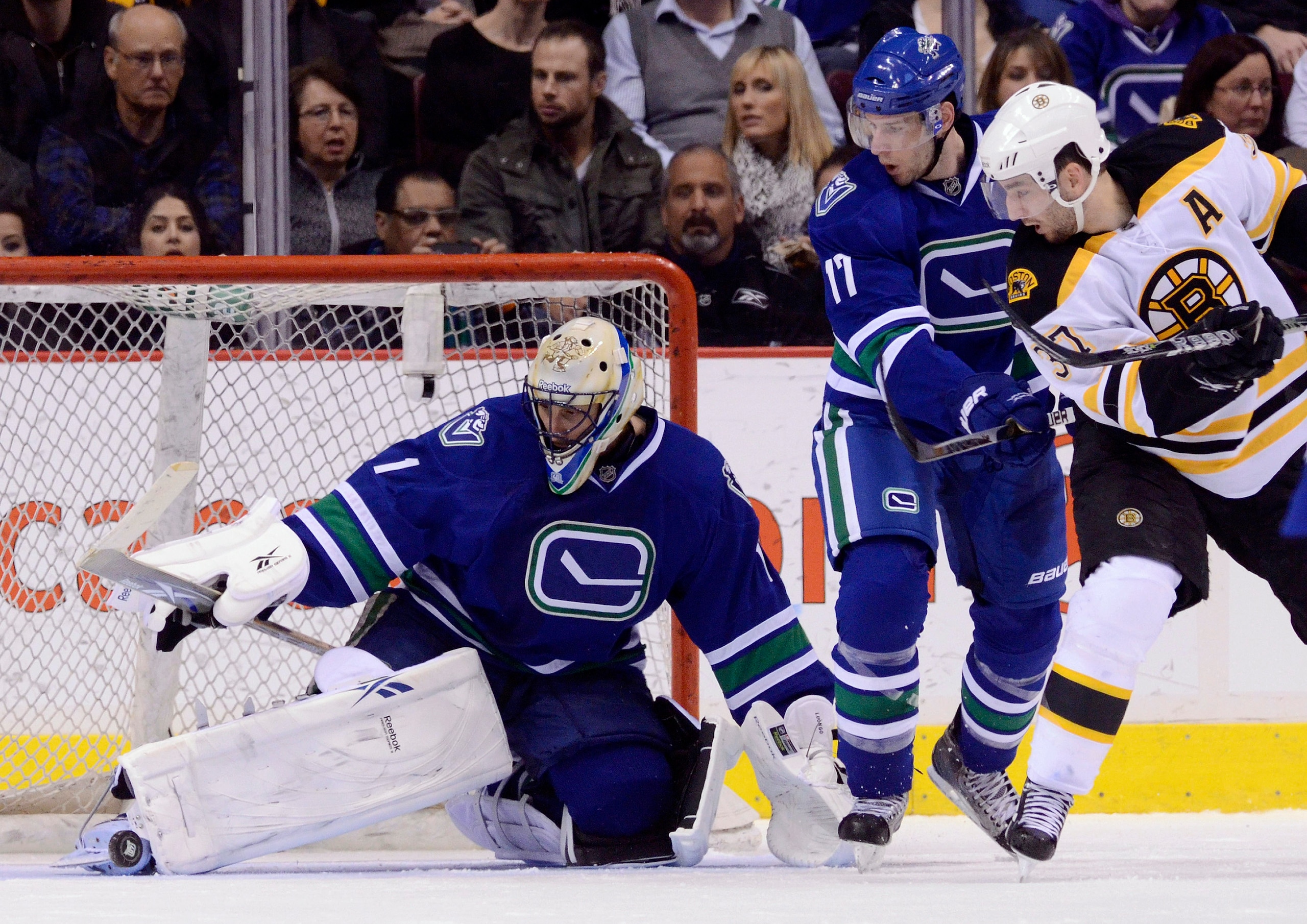 VANCOUVER, CANADA - FEBRUARY 26: Goalie Roberto Luongo #1 of the Vancouver Canucks makes a pad save while Ryan Kesler #17 of the Vancouver Canucks and Patrice Bergeron #37 of the Boston Bruins look on during the second period in NHL action on February 26,