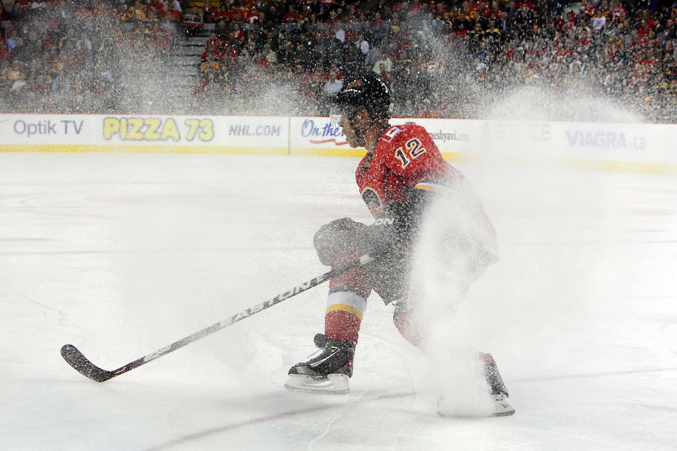 CALGARY,CANADA - FEBRUARY 22:  Jarome Iginla #12 of the Calgary Flames stops as ice sprays up while facing the Boston Bruins during their NHL game at Scotiabank Saddledome, February 22,2011 in Calgary, Alberta, Canada.  (Photo By Dave Sandford/Getty Image