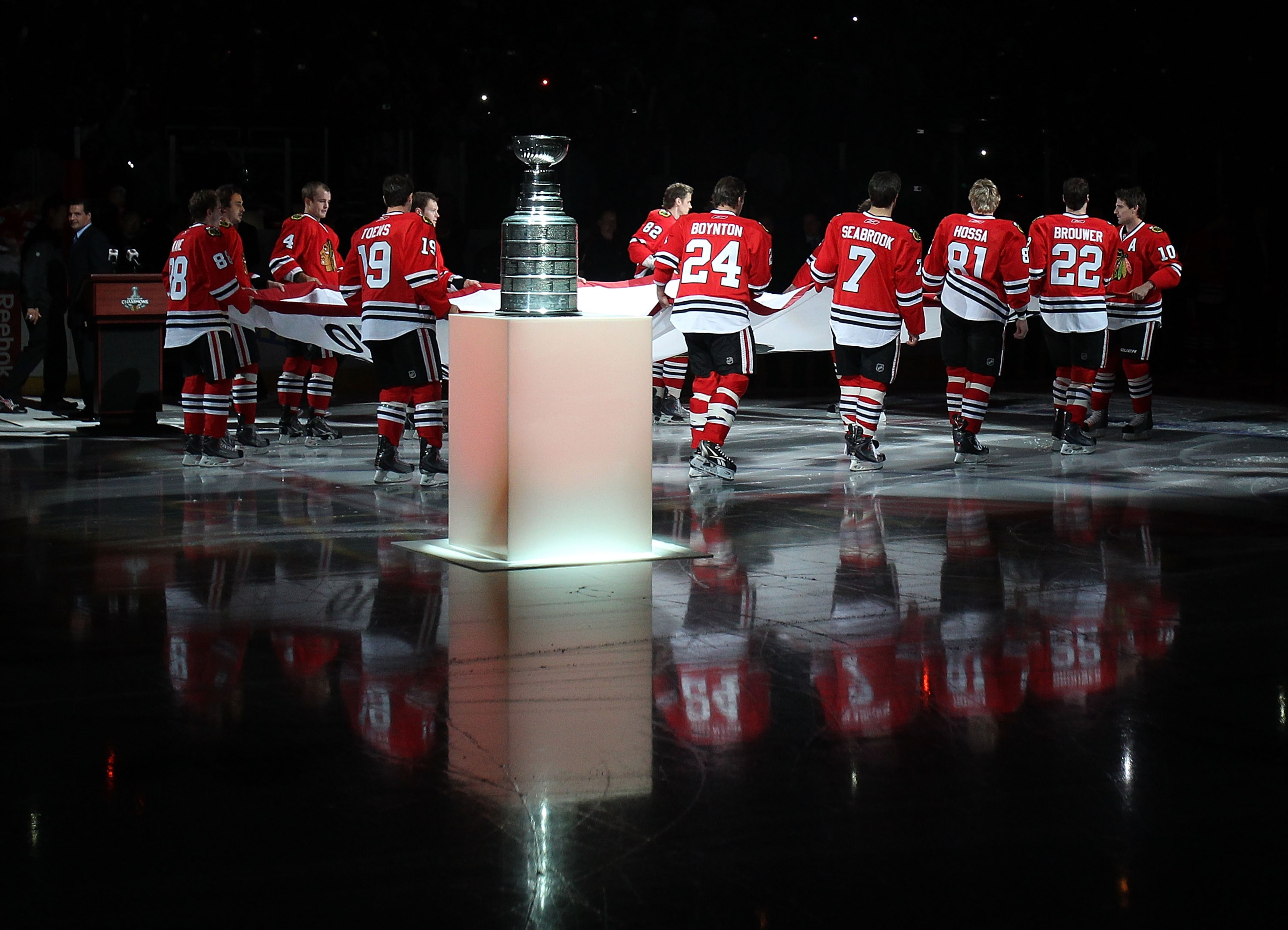 CHICAGO - OCTOBER 09: Members of the Chicago Blackhawks carry the Stanley Cup Championship banner across the ice past the Stanley Cup in a ceremony before the Blackhawks season home opening game against the Detroit Red Wings at the United Center on Octobe