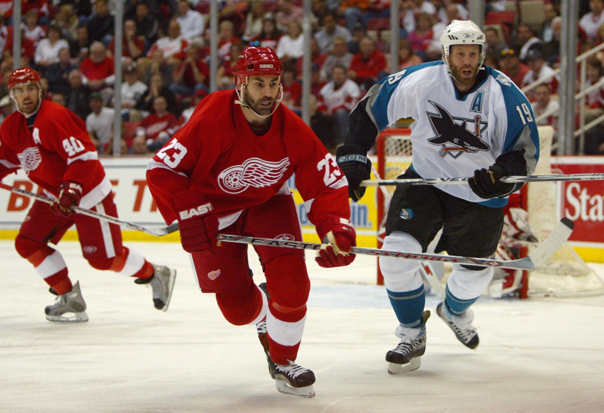DETROIT - APRIL 28:  Mathieu Schneider #23 of the Detroit Red Wings and Joe Thornton #19 of the San Jose Sharks pursue the play during Game 2 of the 2007 NHL Western Conference Semifinals at Joe Louis Arena on April 28, 2007 in Detroit, Michigan. (Photo B