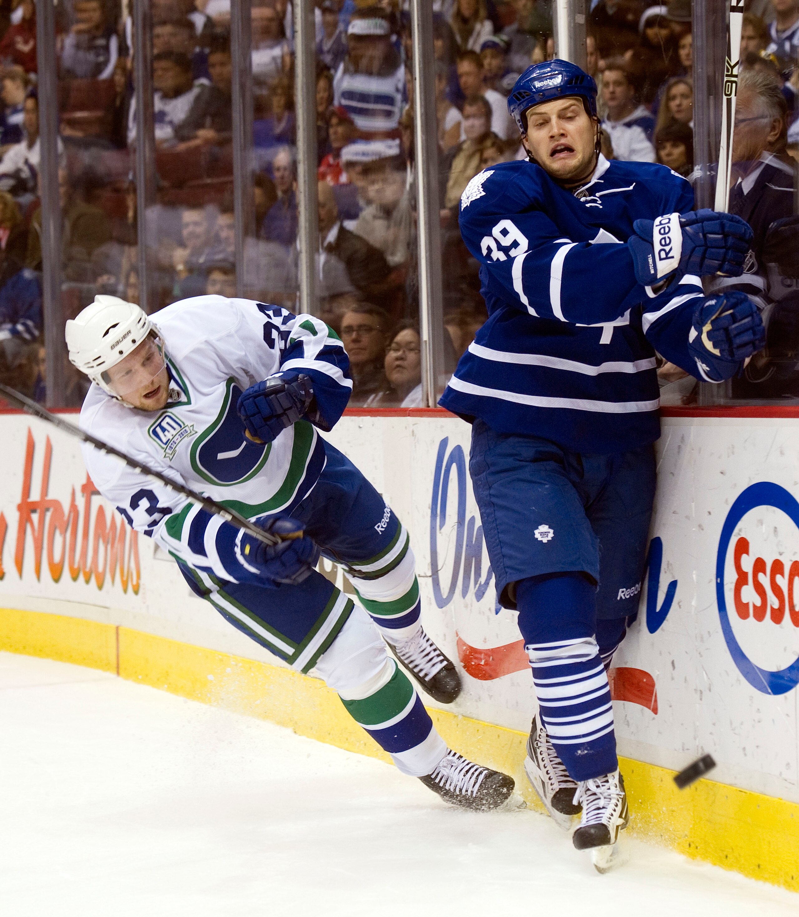 VANCOUVER, CANADA - DECEMBER 18: Alexander Edler #23 of the Vancouver Canucks falls to the ice after getting hit by John Mitchell #39 of the Toronto Maple Leafs after clearing the puck during the first period in NHL action on December 18, 2010 at Rogers A