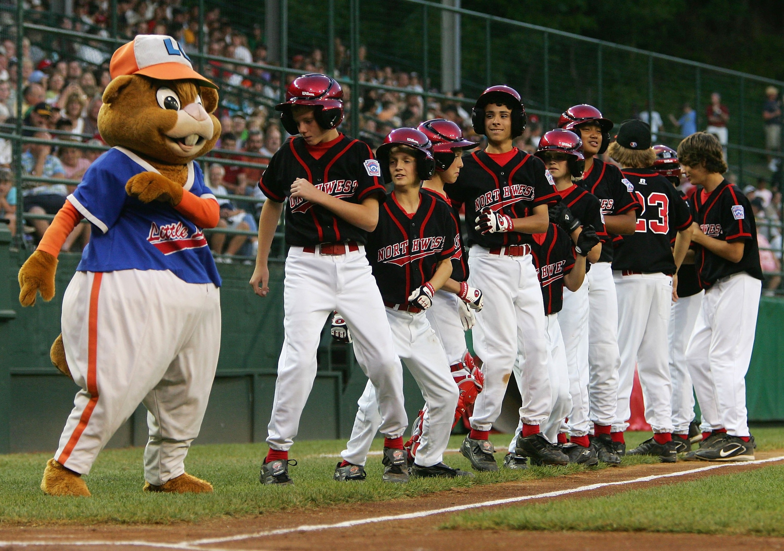 SOUTH WILLIAMSPORT, PA - AUGUST 23:  Members of the Northwest team from Oregon dance with the Little League mascot 'Dugout' before they play the Great Lakes team from Illinois during the United States Semifinal game in the Little League World Series on Au