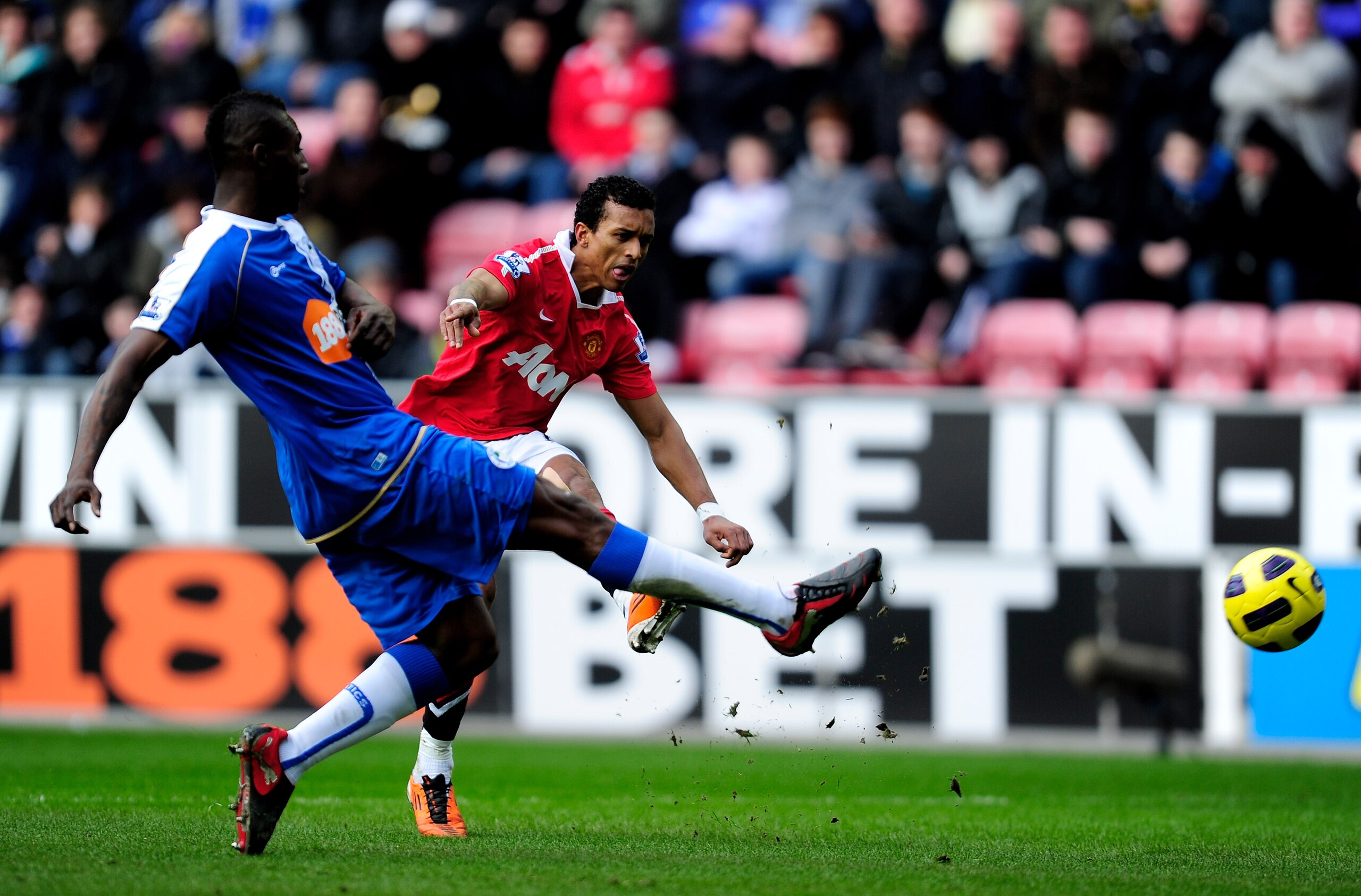 WIGAN, ENGLAND - FEBRUARY 26: Nani of Manchester United shoots past the challenge of Steve Gohouri of Wigan Athletic during the Barclays Premier League match between Wigan Athletic and Manchester United at the DW Stadium on February 26, 2011 in Wigan, En WIGAN, ENGLAND - FEBRUARY 26: Nani of Manchester United shoots past the challenge of Steve Gohouri of Wigan Athletic during the Barclays Premier League match between Wigan Athletic and Manchester United at the DW Stadium on February 26, 2011 in Wigan, En