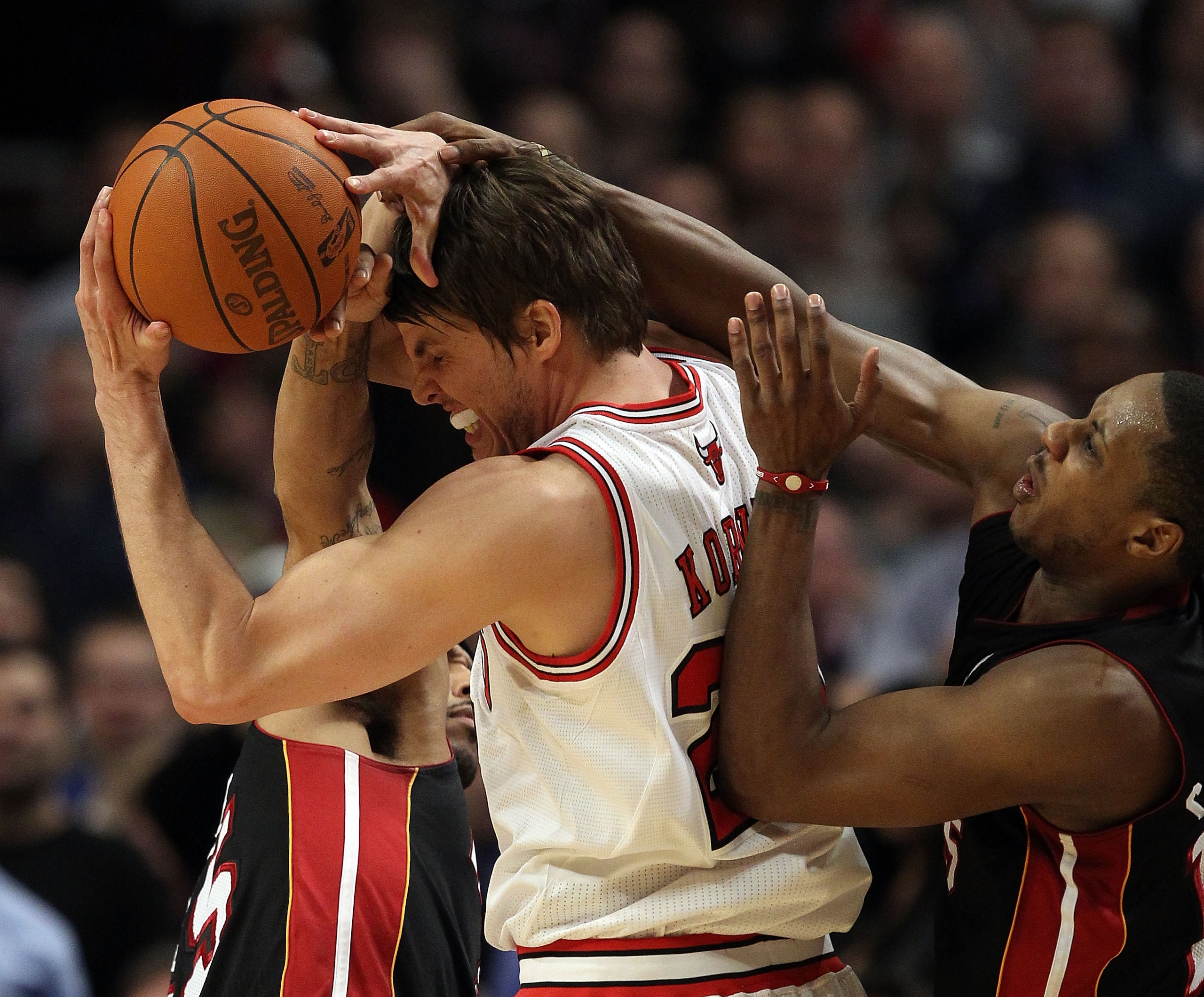 CHICAGO, IL - FEBRUARY 24: Kyle Korver #26 of the Chicago Bulls is fouled by Eddie House #55 (L) and Mario Chalmers #15 of the Miami Heat at the United Center on February 24, 2011 in Chicago, Illinois. The Bulls defeated the Heat 93-89. NOTE TO USER: User
