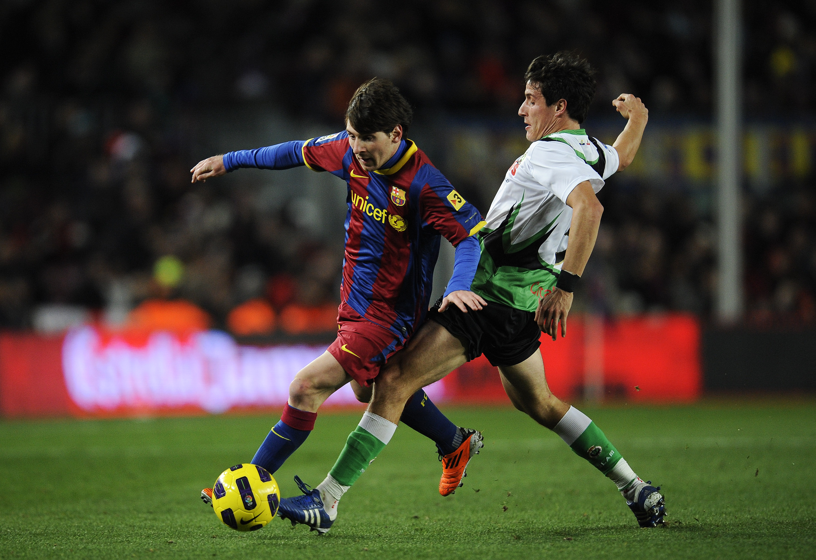 BARCELONA, SPAIN - JANUARY 22:  Lionel Messi of Barcelona (R) duels for the ball against Christian Fernandez of Racing Santander during the La Liga match between Barcelona and Racing Santander at Camp Nou on January 22, 2011 in Barcelona, Spain.  Barcelon