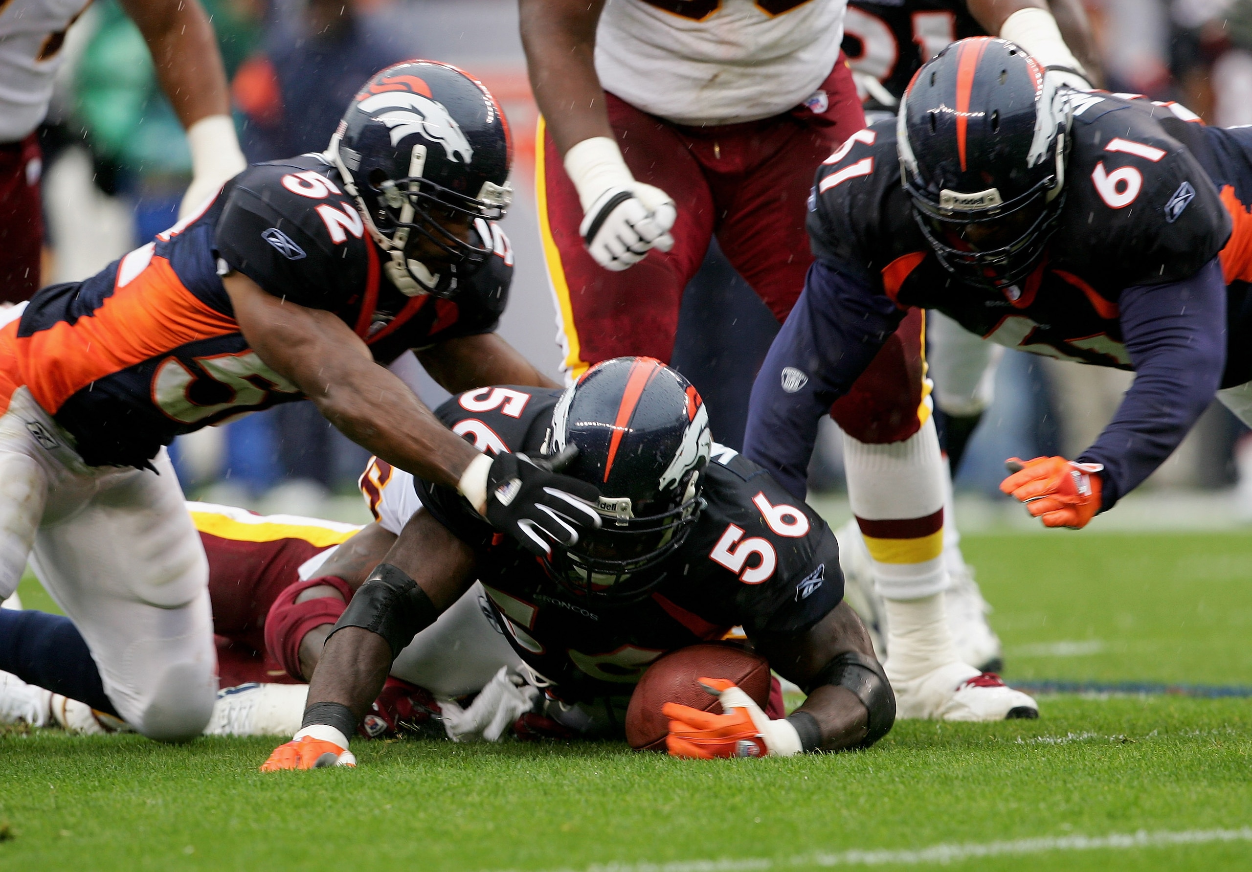 DENVER - OCTOBER 09:   Al Wilson #56 of the Denver Broncos recovers a fumble by Clinton Portis #26 of  the Washington Redskins as teammates Ian Gold #52 and Gerard Warren #61 give support during NFL action at Invesco Field at Mile High on October 9, 2005