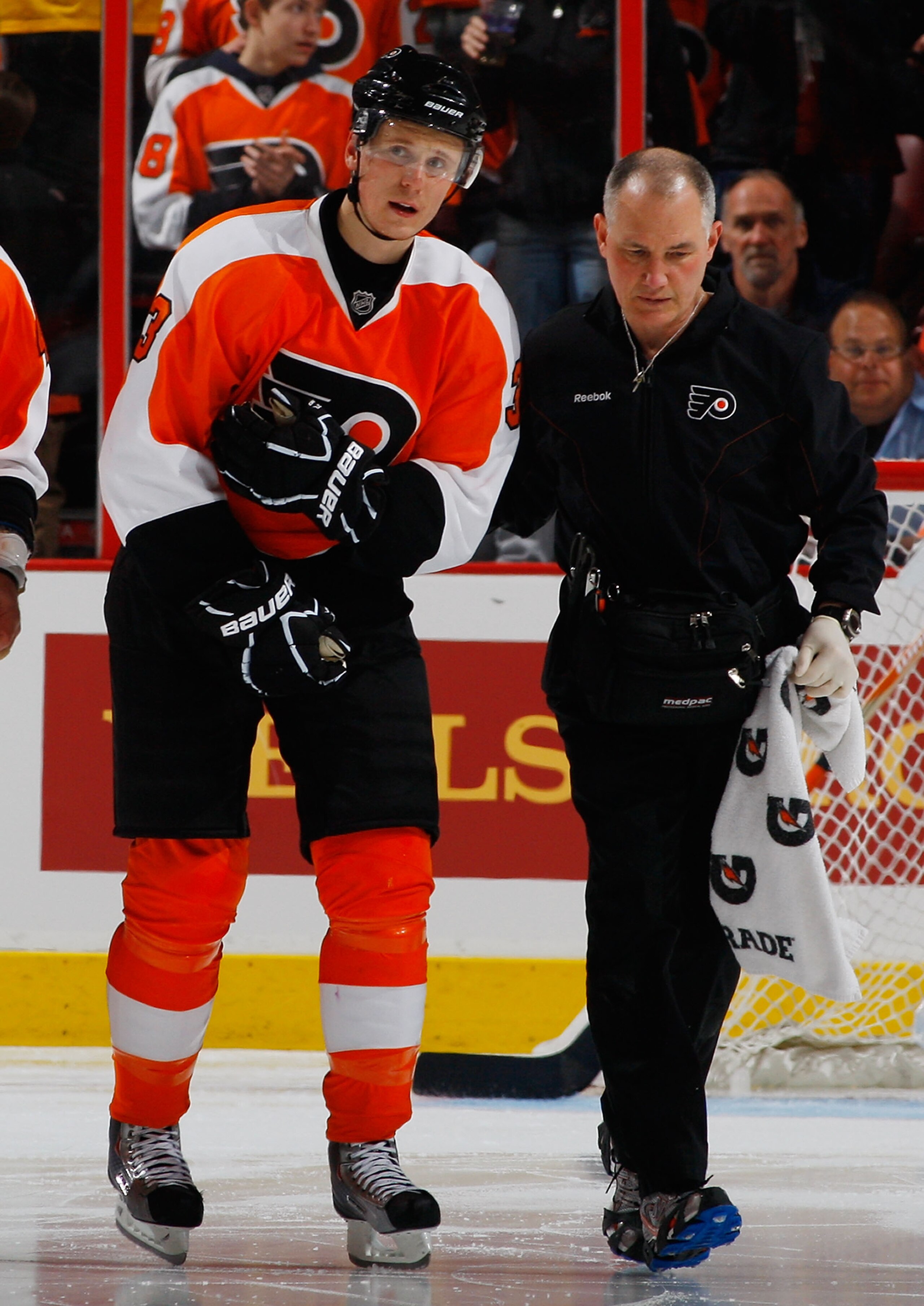 PHILADELPHIA - FEBRUARY 22:  Oskars Bartulis #3 of the Philadelphia Flyers is helped off the ice by Athletic Trainer Jim McCrossin after being injured against the Phoenix Coyotes on February 22, 2011 at the Wells Fargo Center in Philadelphia, Pennsylvania