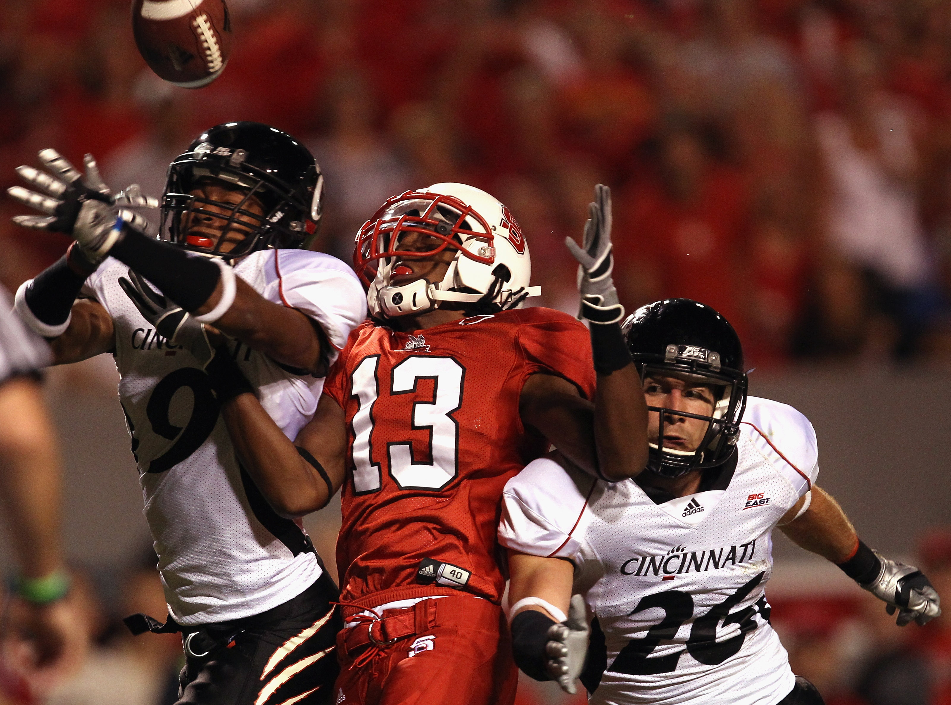 RALEIGH, NC - SEPTEMBER 16: Teammates Dominique Battle #9 and Drew Frey #26 of the Cincinnati Bearcats break up a pass to Owen Spencer #13 of the North Carolina State Wolfpack during their game at Carter-Finley Stadium on September 16, 2010 in Raleigh, N