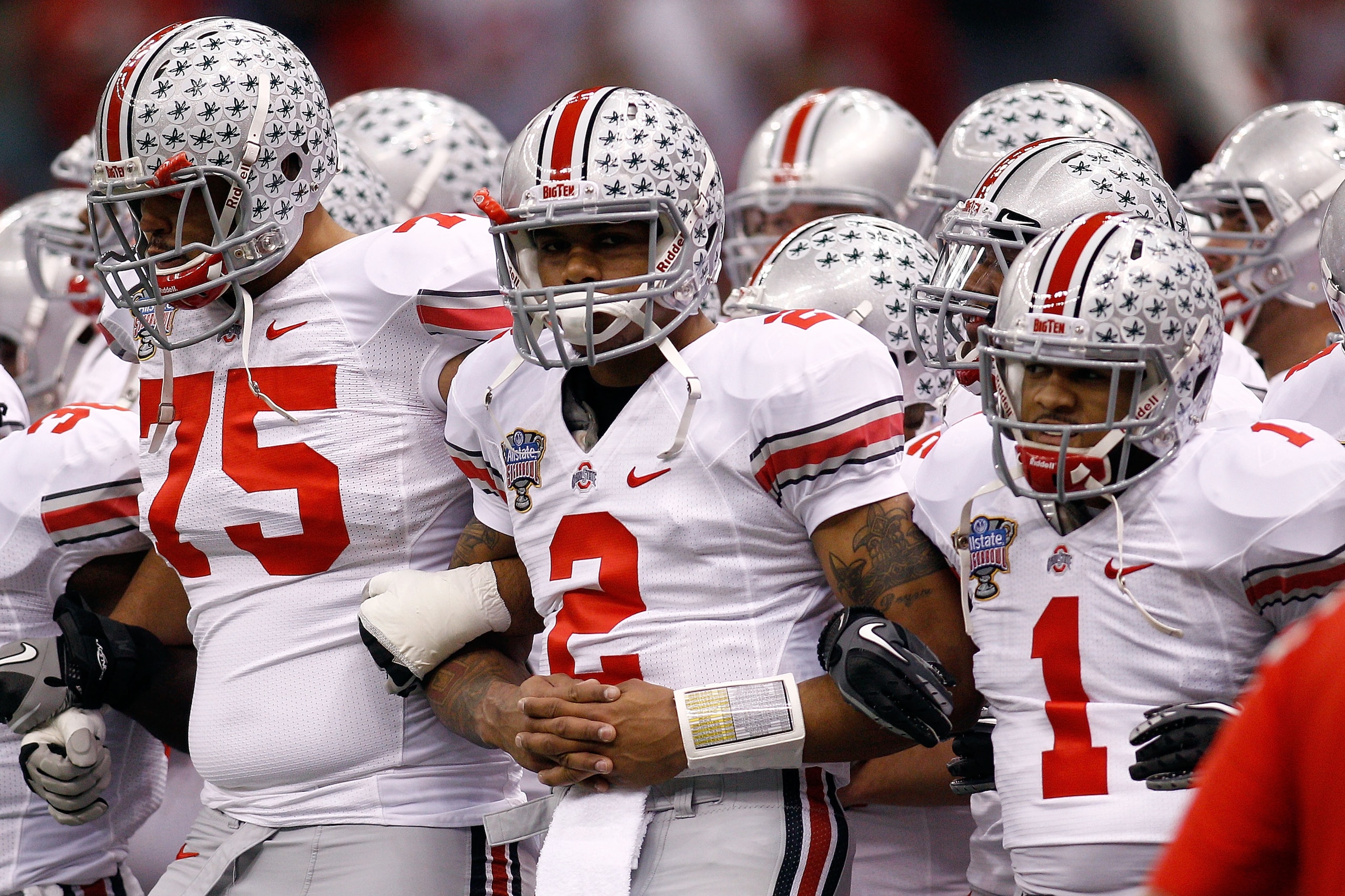 NEW ORLEANS, LA - JANUARY 04:  (R-L) Dan Herron #1, Terrelle Pryor #2 and Mike Adams #75 of the Ohio State Buckeyes gather with teammates before taking on the Arkansas Razorbacks during the Allstate Sugar Bowl at the Louisiana Superdome on January 4, 2011
