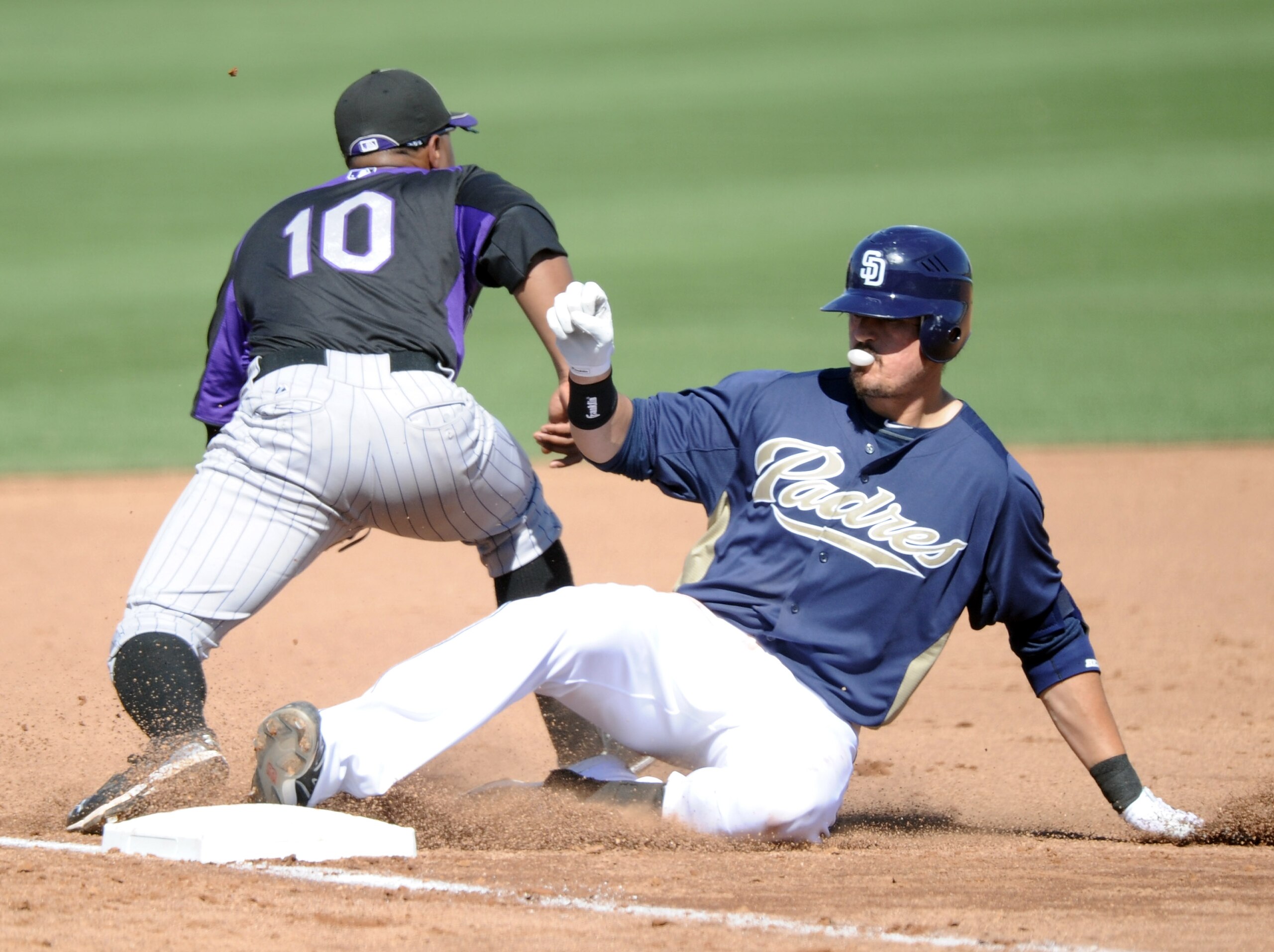 PEORIA, AZ - MARCH 02:  Jorge Cantu #32 of the San Diego Padres slides in for a triple in front of Chirs Nelson #10 of the Colorado Rockies to score two runs in the fourth inning during spring training at Peoria Stadium on March 2, 2011 in Peoria, Arizona