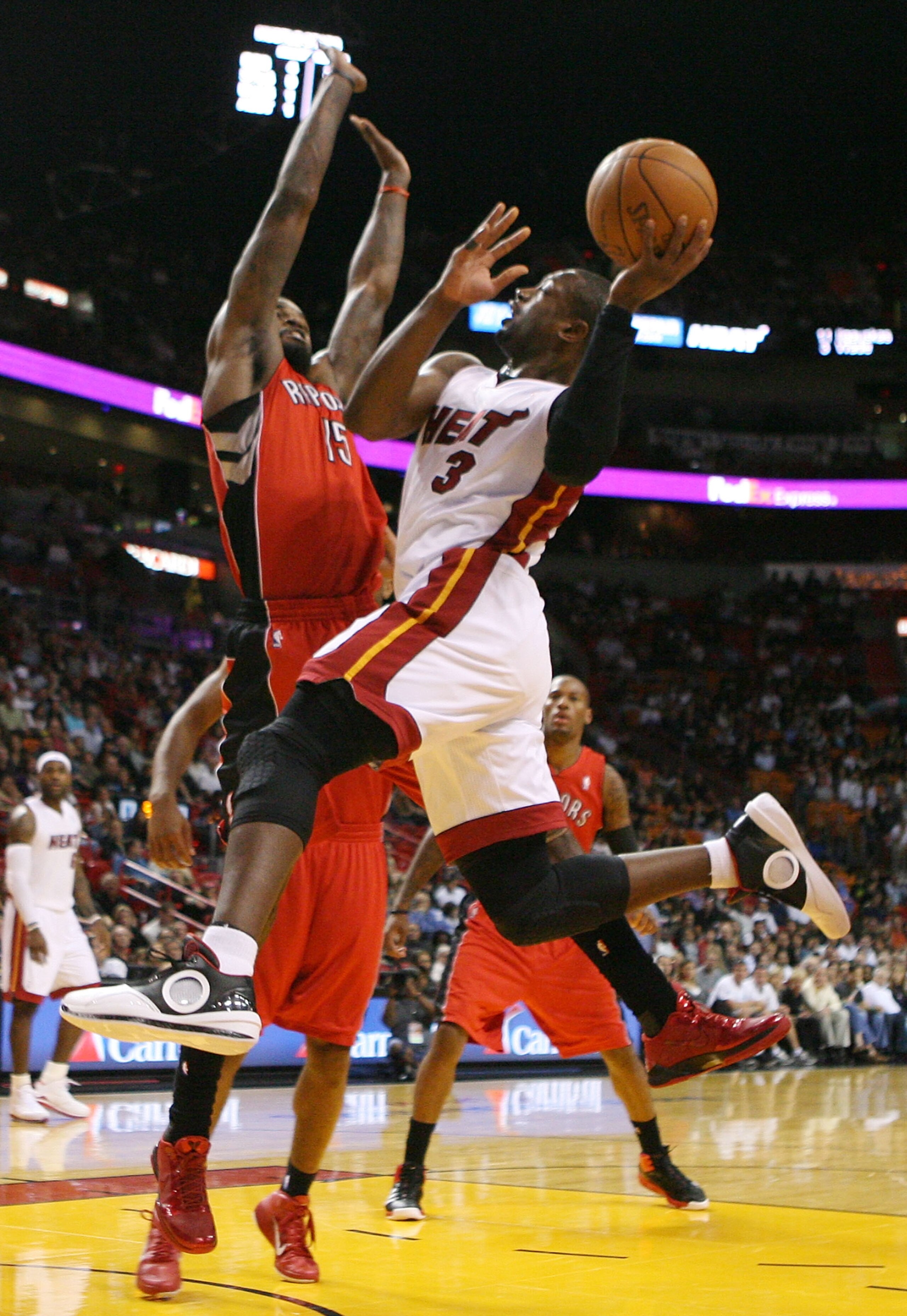 MIAMI - NOVEMBER 13:  Guard Dwyane Wade #3 of the Miami Heat is fouled by center Amir Johnson #15  of the Toronto Raptors at American Airlines Arena on November 13, 2010 in Miami, Florida. NOTE TO USER: User expressly acknowledges and agrees that, by down