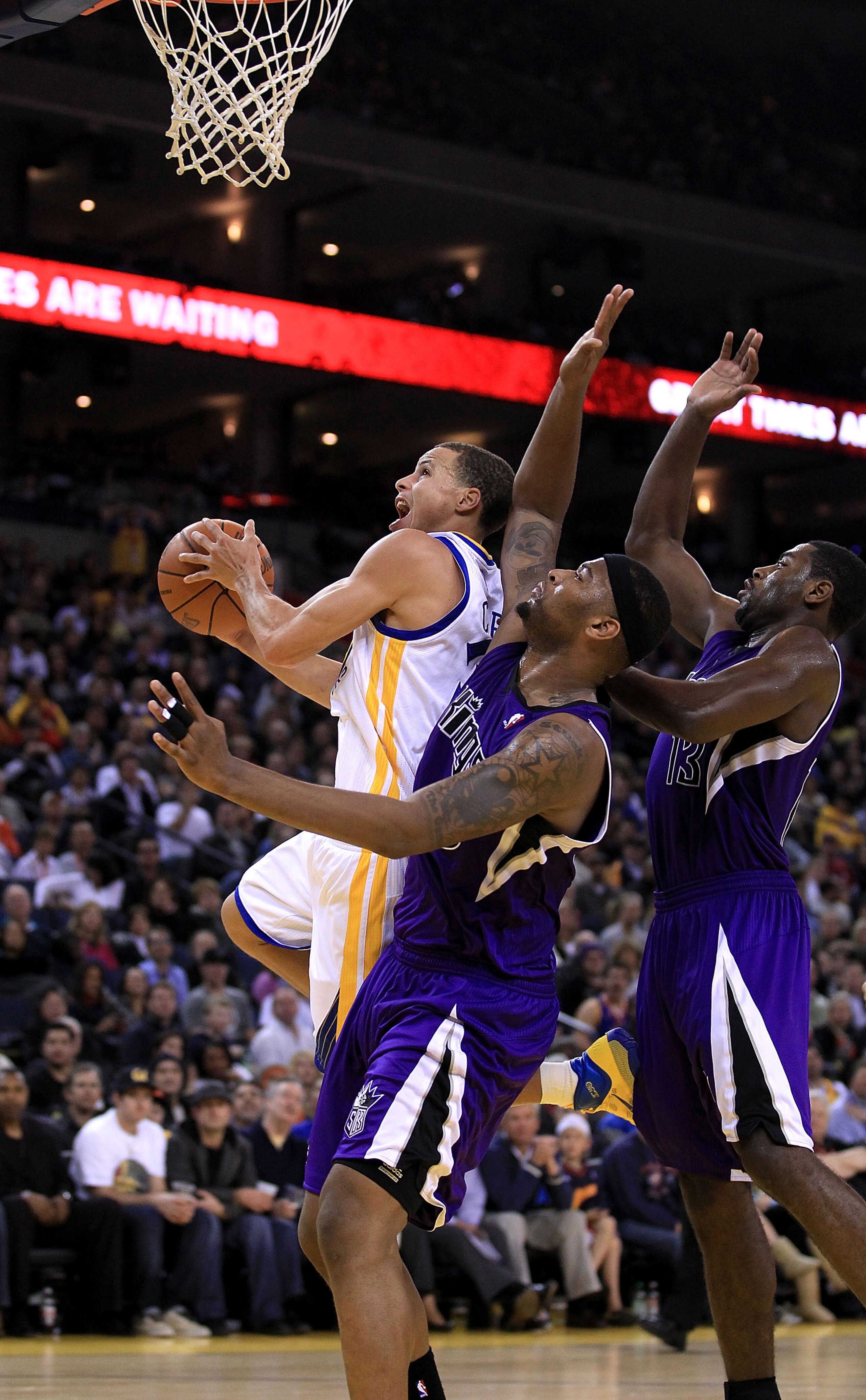 OAKLAND, CA - JANUARY 21:  Stephen Curry #30 of the Golden State Warriors drives on DeMarcus Cousins #15 and Tyreke Evans #13 of the Sacramento Kings at Oracle Arena on January 21, 2011 in Oakland, California. NOTE TO USER: User expressly acknowledges and