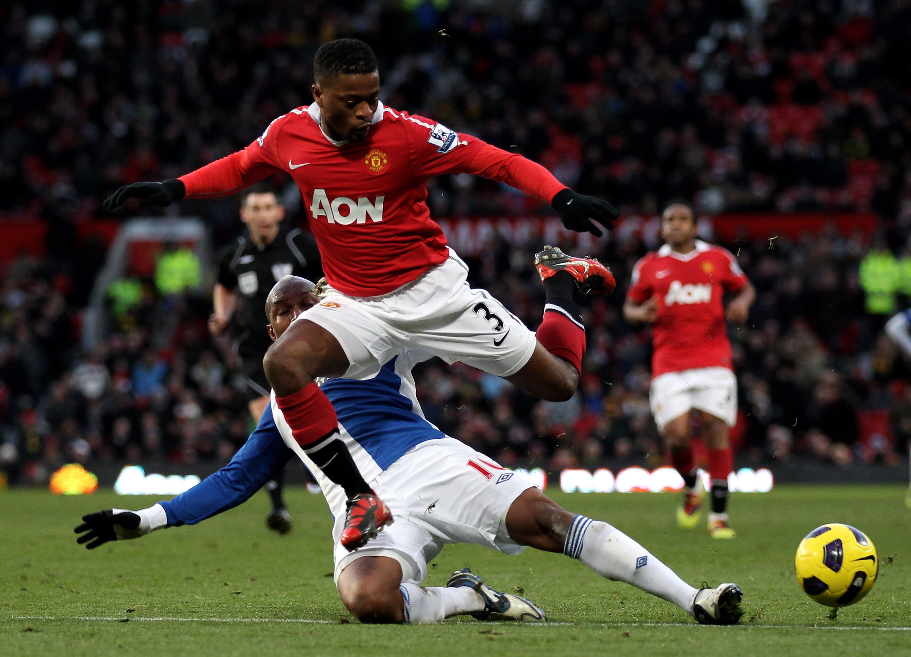 MANCHESTER, ENGLAND - NOVEMBER 27:   Patrice Evra of Manchester United hurdles the challenge of El Hadji Diouf of Blackburn Rovers during the Barclays Premier League match between Manchester United and Blackburn Rovers at Old Trafford on November 27, 2010