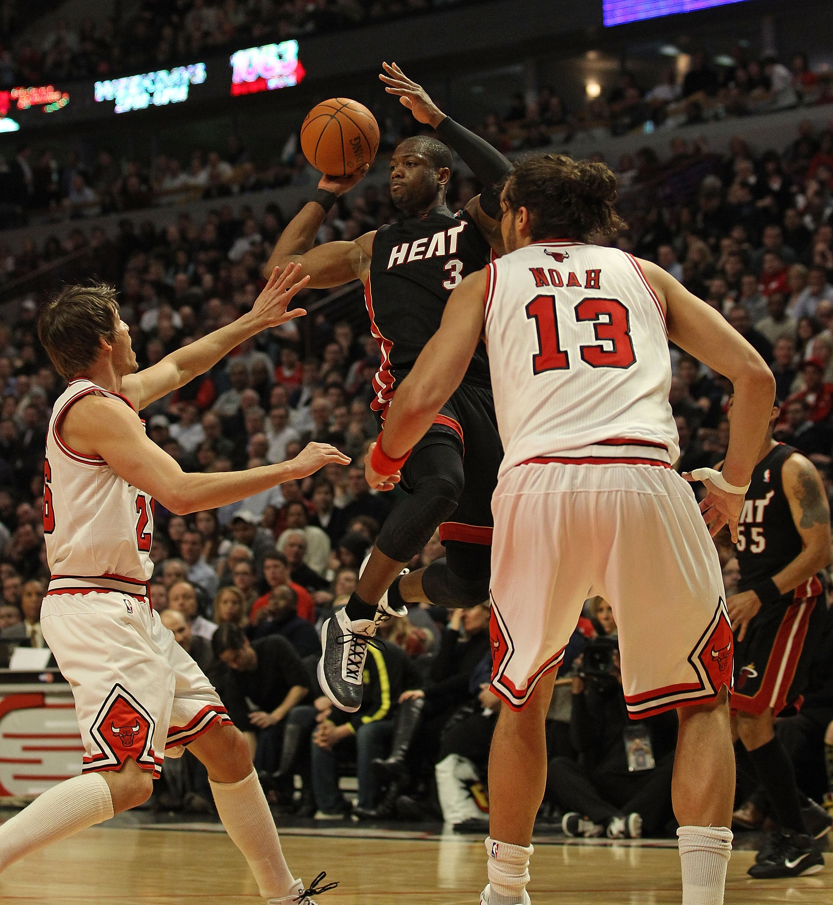 CHICAGO, IL - FEBRUARY 24: Dwyane Wade #3 of the Miami Heat leaps to pass over Kyle Krover #26 and Joakim Noah #13 of the Chicago Bulls at the United Center on February 24, 2011 in Chicago, Illinois. The Bulls defeated the Heat 93-89. NOTE TO USER: User e