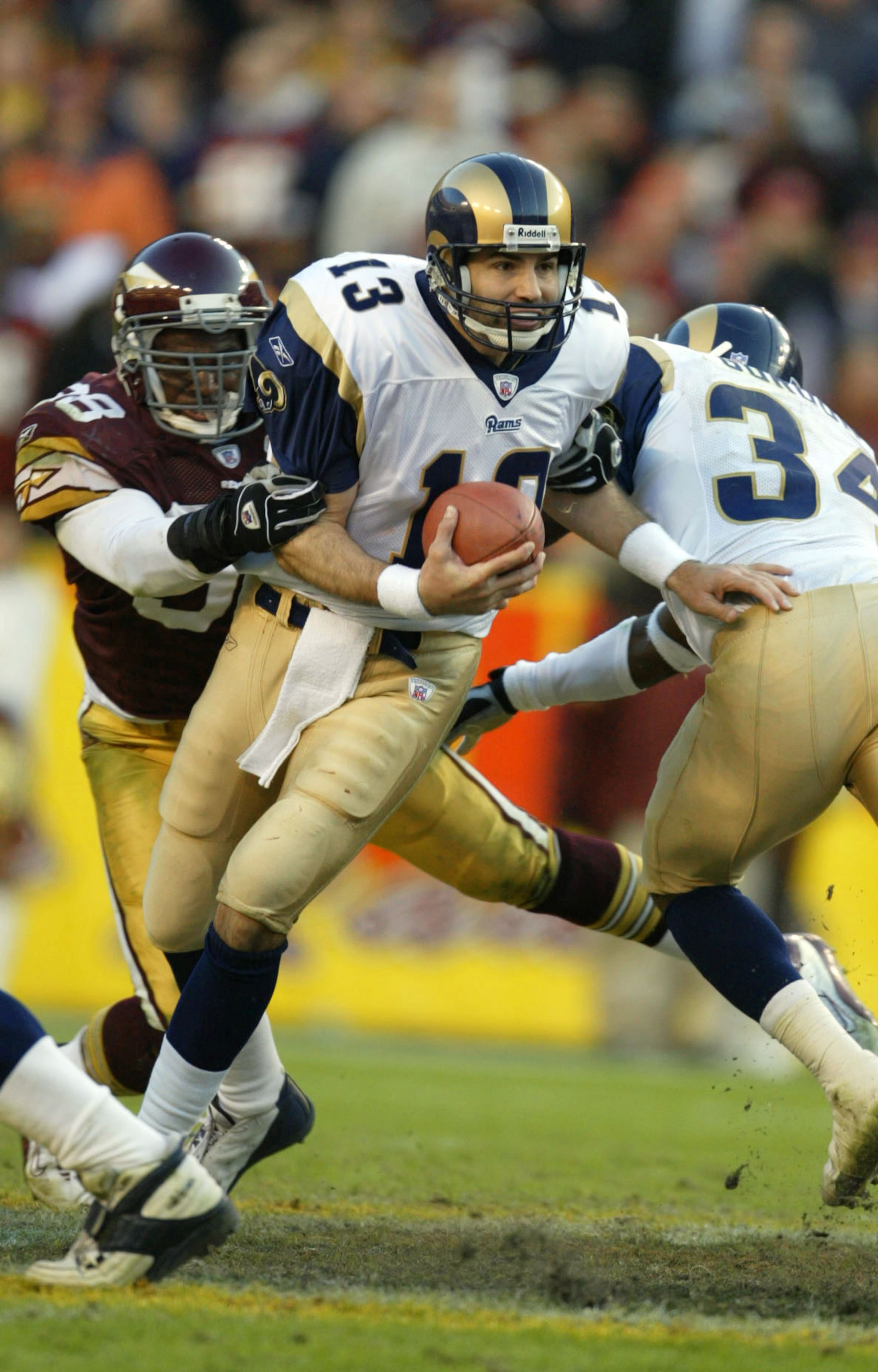 LANDOVER, MD - NOVEMBER 24: Quarterback Kurt Warner #13 of the St. Louis Rams eludes the grasp of #58 Antonio Pierce #58 of the Washington Redskins in the 4th quarter on November 24, 2002 at FedEx Field in Landover Maryland. (Photo by Al Bello/Getty Ima LANDOVER, MD - NOVEMBER 24: Quarterback Kurt Warner #13 of the St. Louis Rams eludes the grasp of #58 Antonio Pierce #58 of the Washington Redskins in the 4th quarter on November 24, 2002 at FedEx Field in Landover Maryland. (Photo by Al Bello/Getty Ima
