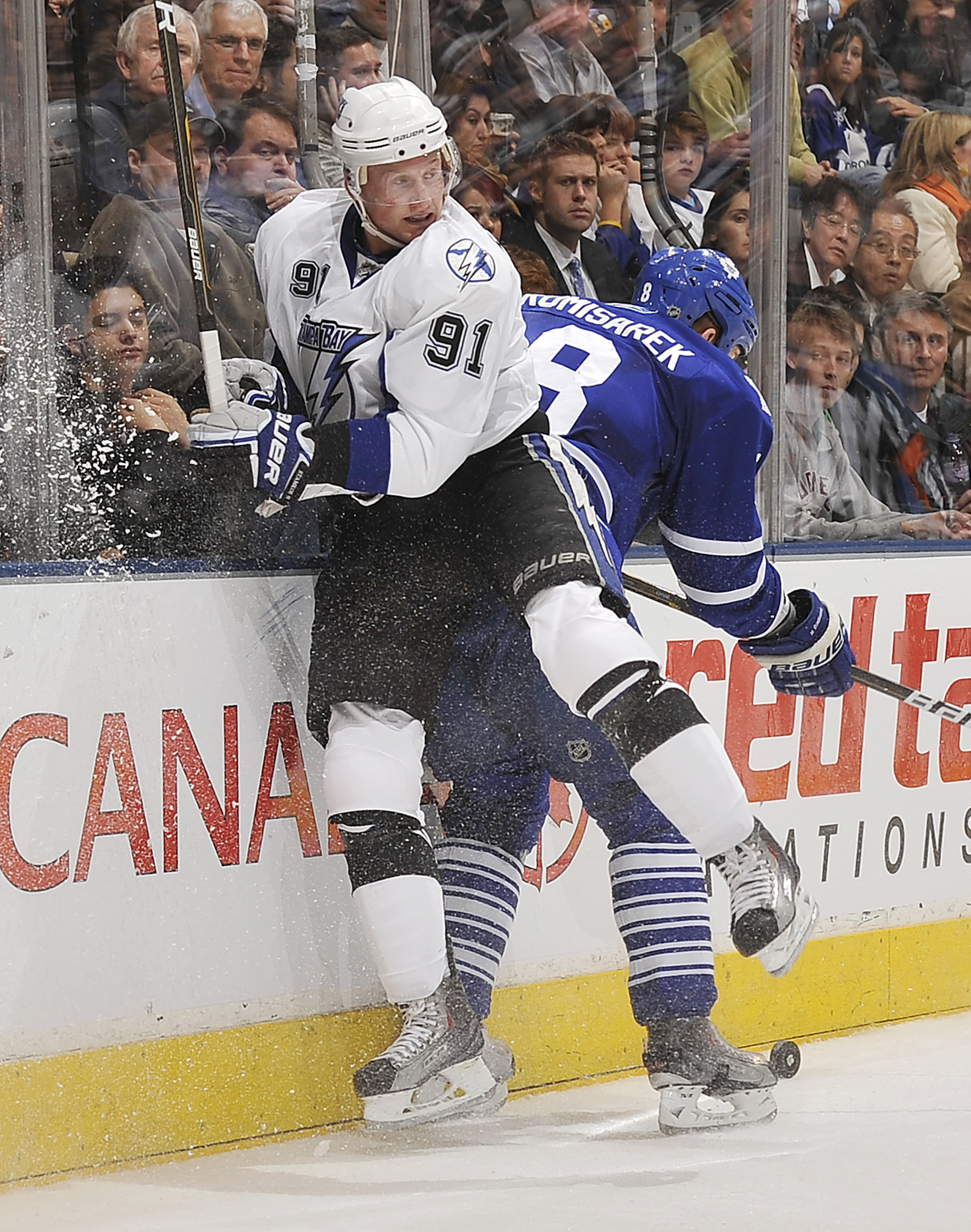 TORONTO, CANADA - NOVEMBER 30:  Steven Stamkos #91 of the Tampa Bay Lightning checks Mike Komisarek #8 of the Toronto Maple Leafs during game action November 30, 2010 at the Air Canada Centre in Toronto, Ontario, Canada. (Photo by Abelimages/Getty Images)