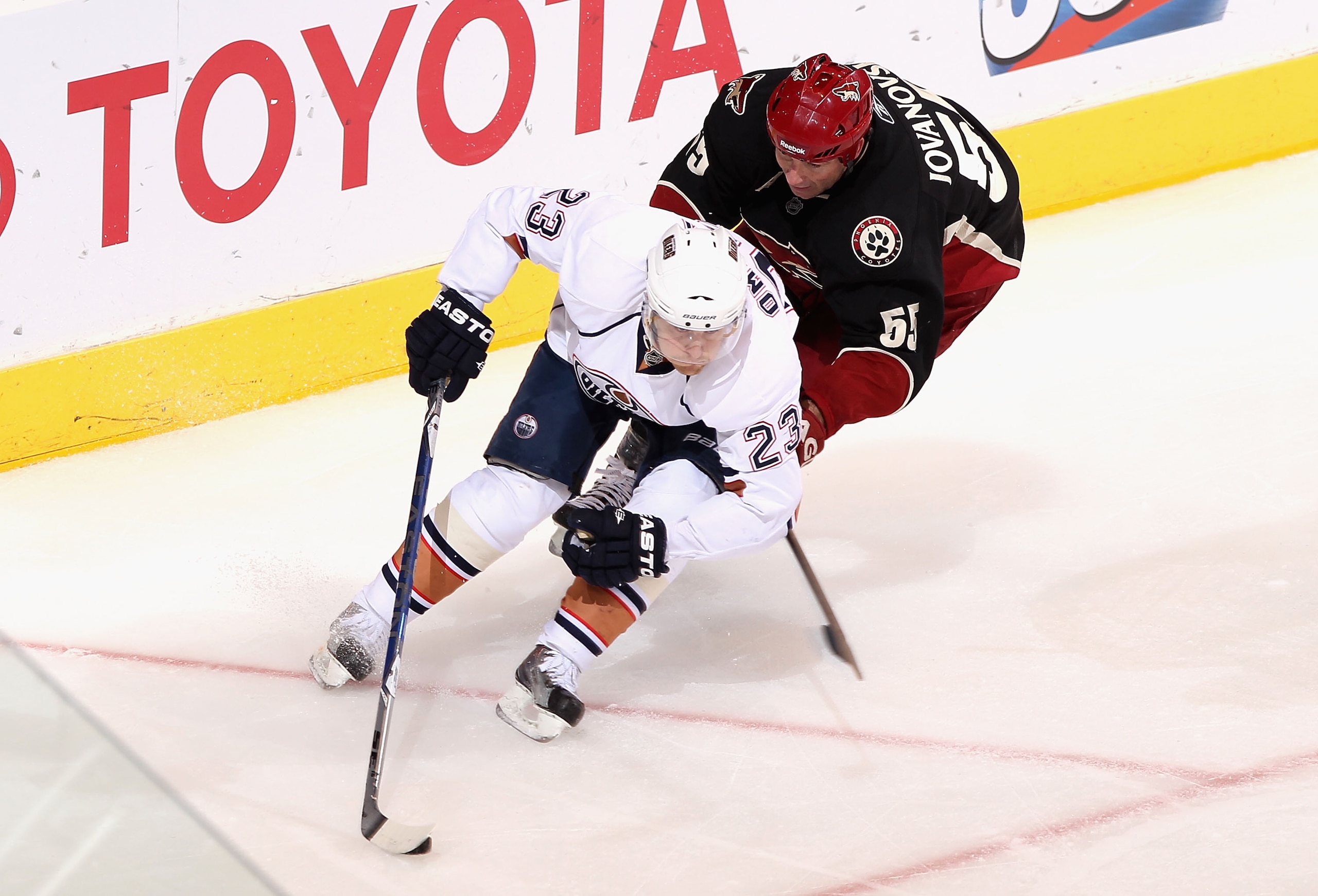 GLENDALE, AZ - JANUARY 25:  Linus Omark #23 of the Edmonton Oilers skates with the puck past Ed Jovanovski #55 of the Phoenix Coyotes during the NHL game at Jobing.com Arena on January 25, 2011 in Glendale, Arizona.  The Oilers defeated the Coyotes 4-3.