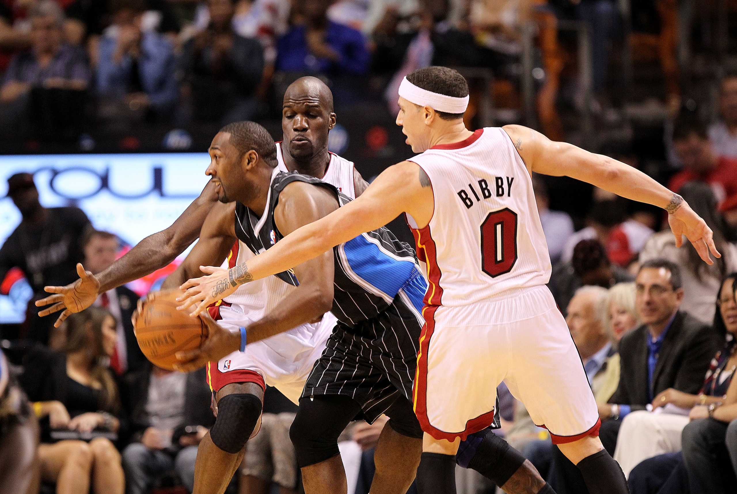 MIAMI, FL - MARCH 03:  Gilbert Arenas #1 of the Orlando Magic passes around Mike Bibby #0 and Joel Anthony #50 of the Miami Heat during a game at American Airlines Arena on March 3, 2011 in Miami, Florida. NOTE TO USER: User expressly acknowledges and agr