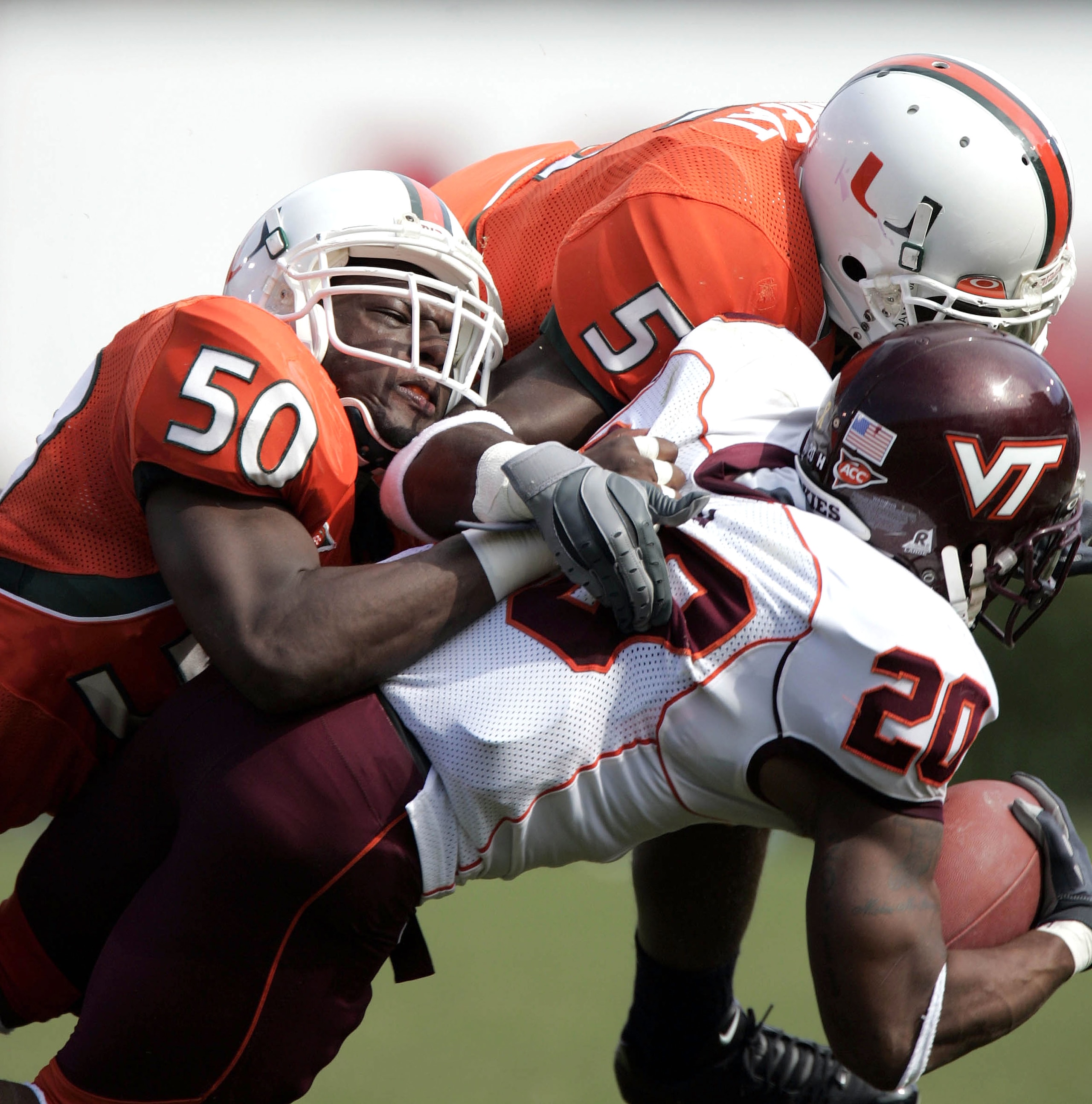 MIAMI - DECEMBER 4:  Tail back Mike Imoh #20 of Virgina Tech is stopped by Roger McIntosh #50 and Greg Threat #5 of the University of Miami on December 4, 2004 at the Orange Bowl in Miami, Florida.  (Photo by Eliot J. Schechter/Getty Images)