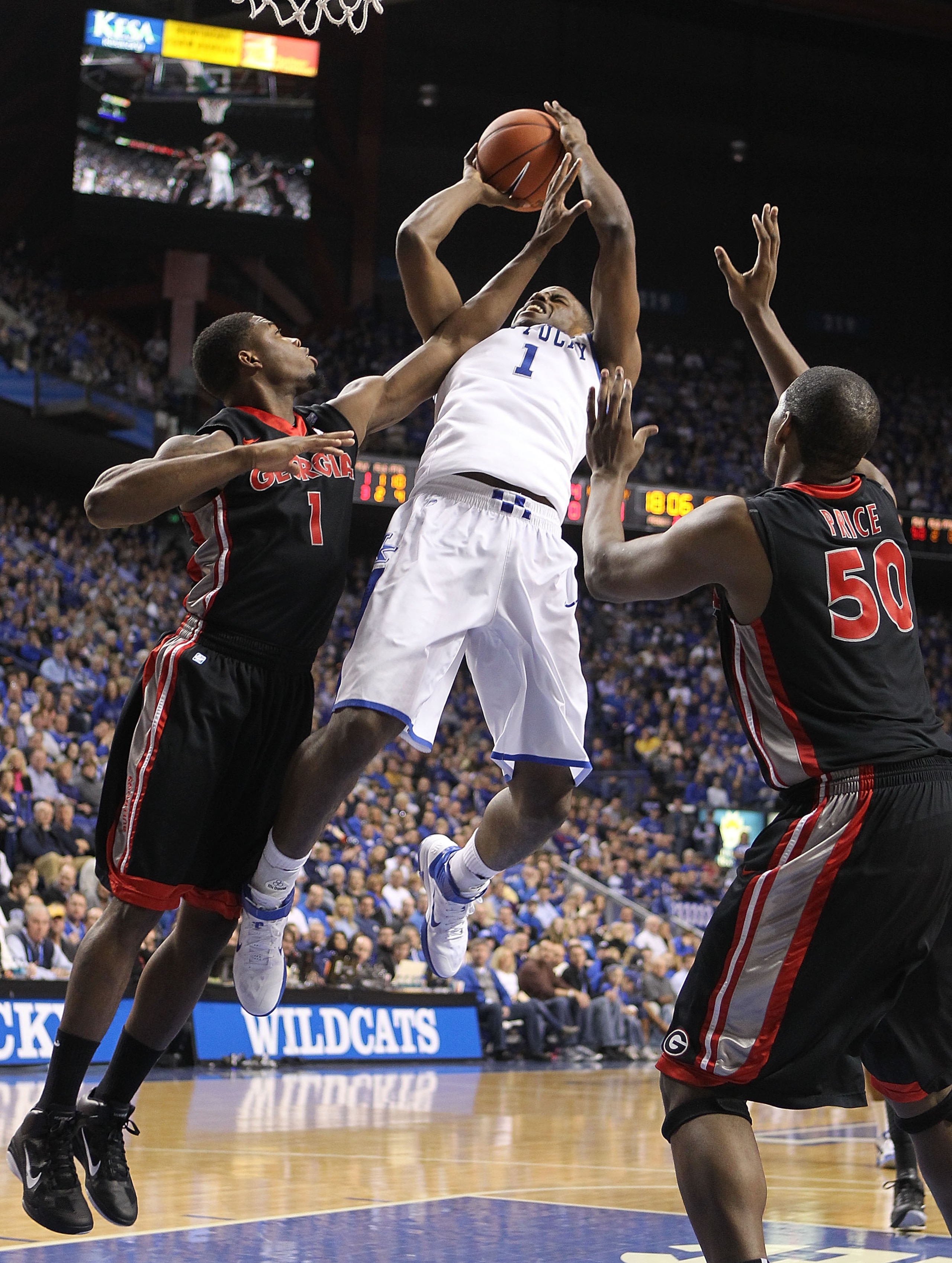 LEXINGTON, KY - JANUARY 29: Darius Miller #1 of the Kentucky Wildcats shoots the ball while defended by Travis Leslie #1 and Jeremy Price #50 of the Georgia Bulldogs during the SEC game at Rupp Arena on January 29, 2011 in Lexington, Kentucky. Kentucky wo