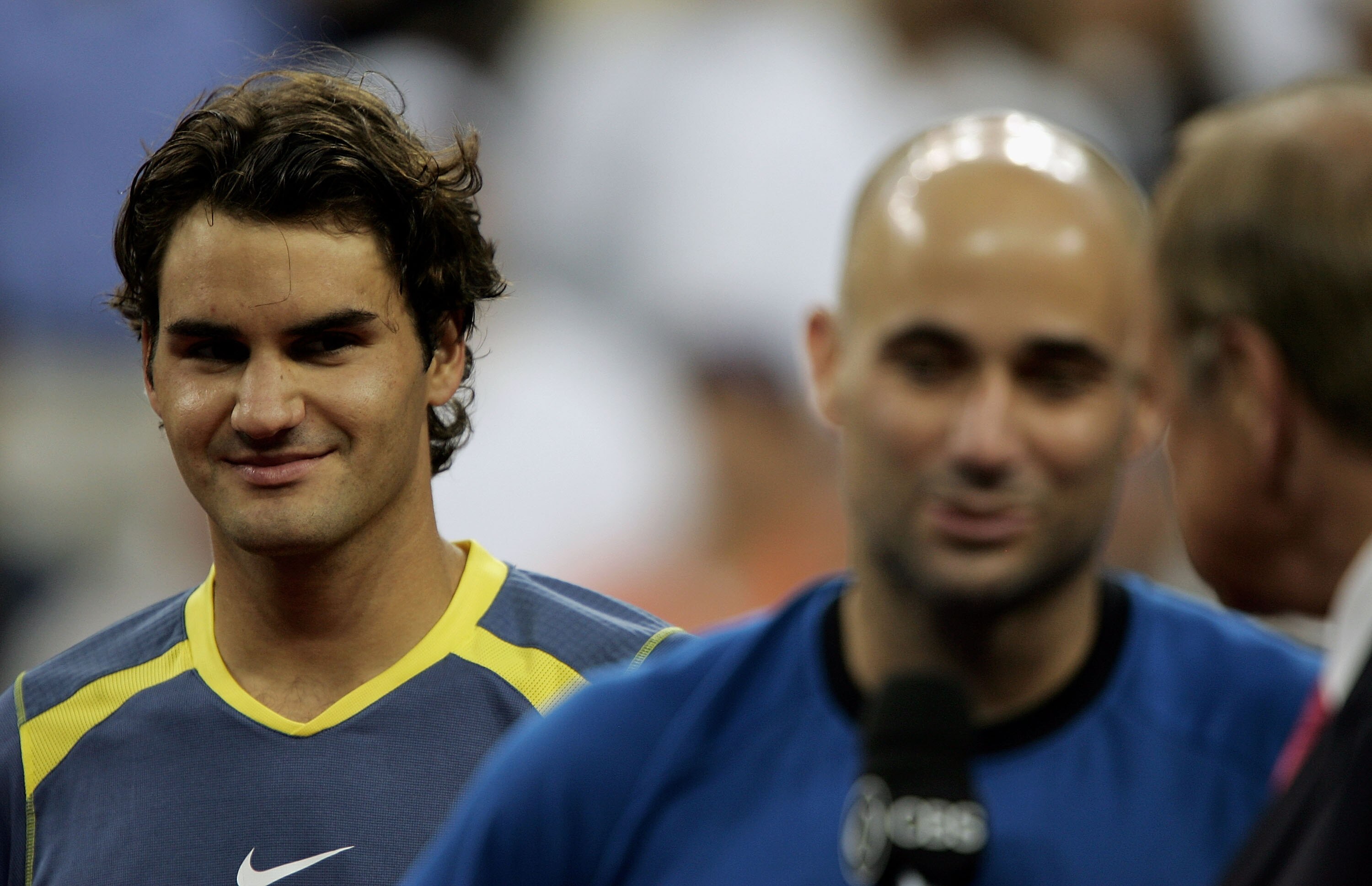 NEW YORK - SEPTEMBER 11:  (L-R)Roger Federer of Switzerland smiles as Andre Agassi is interviewed after Federer won the men's final of the US Open at the USTA National Tennis Center in Flushing Meadows Corona Park on September 11, 2005 in the Flushing nei