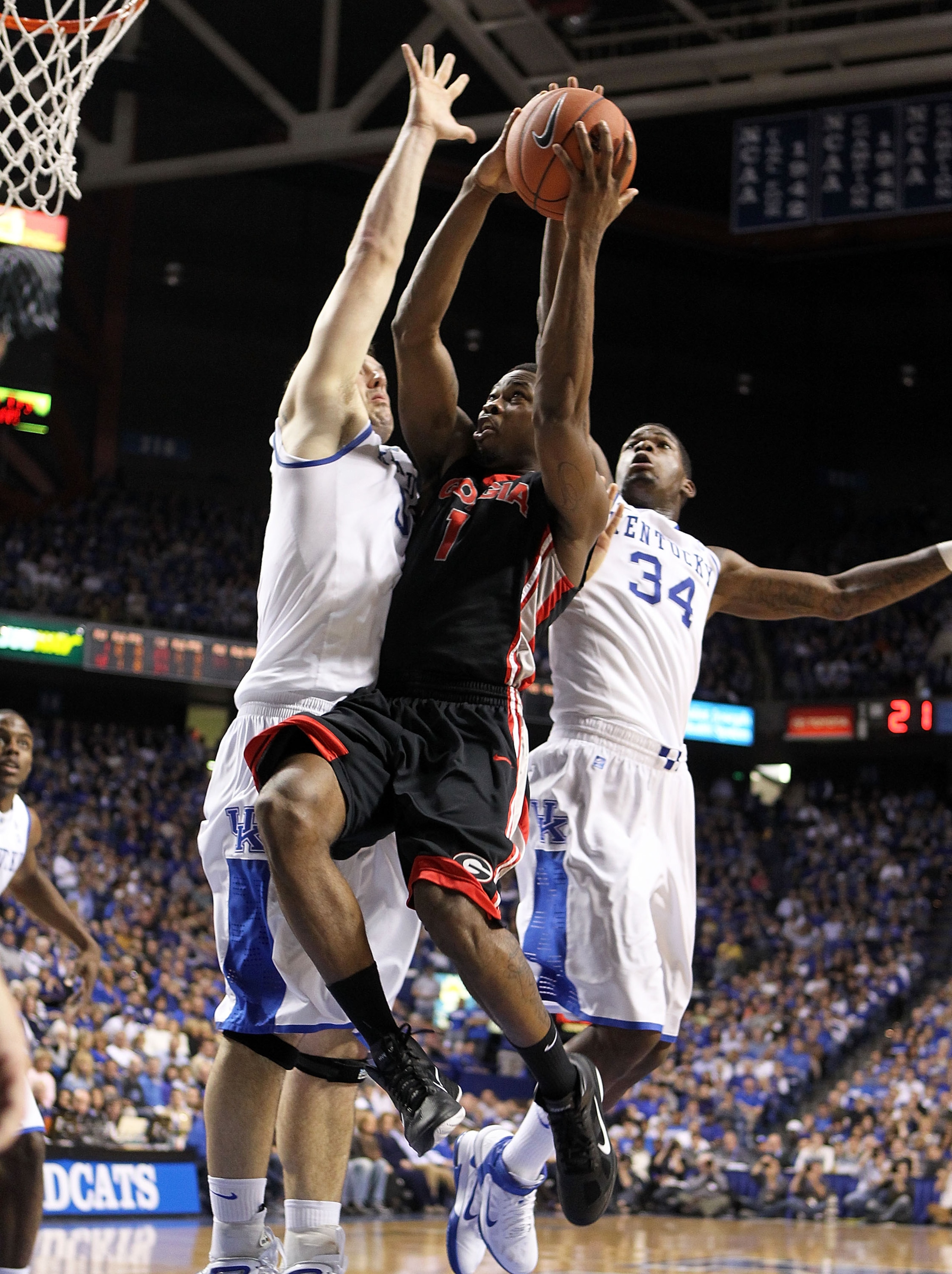 LEXINGTON, KY - JANUARY 29:  Travis Leslie #1 of  the Georgia Bulldogs shoots the ball while defended by Josh Harrellson #55 and DeAndre Liggins #34 of the Kentucky Wildcats during the SEC game against at Rupp Arena on January 29, 2011 in Lexington, Kentu