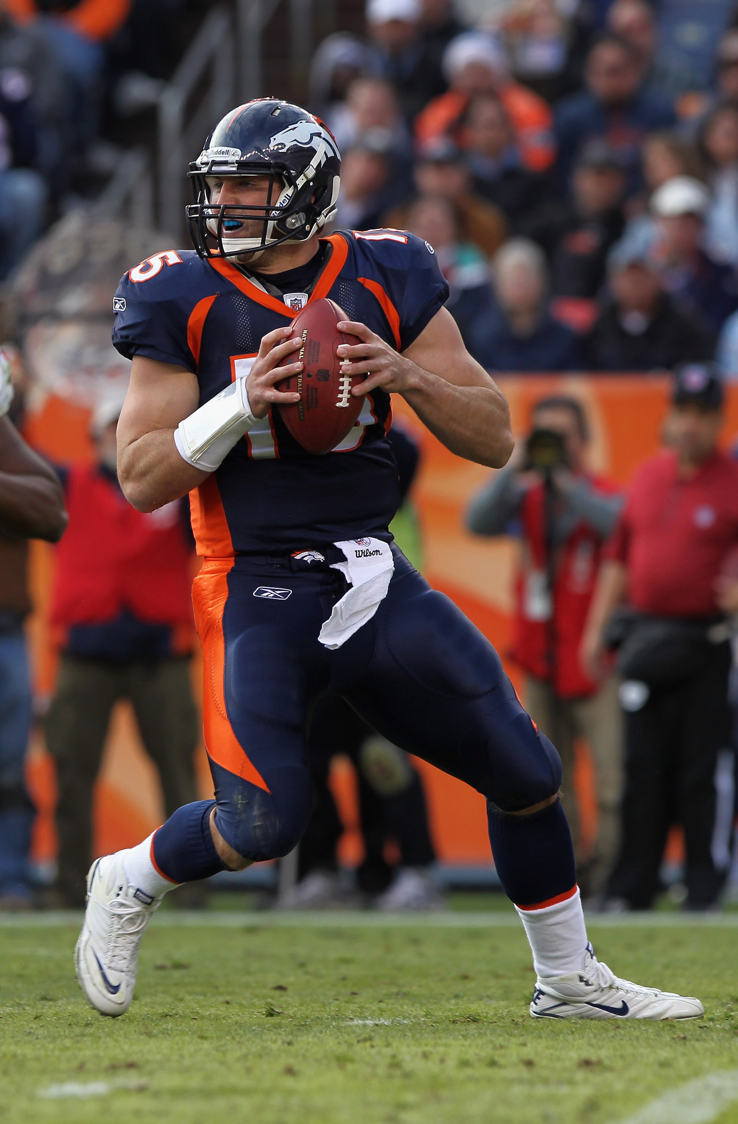 DENVER - DECEMBER 26:  Quarterback Tim Tebow #15 of the Denver Broncos rolls out and looks to deliver a pass against the Houston Texas at INVESCO Field at Mile High on December 26, 2010 in Denver, Colorado. The Broncos defeated the Texans 24-23.  (Photo b