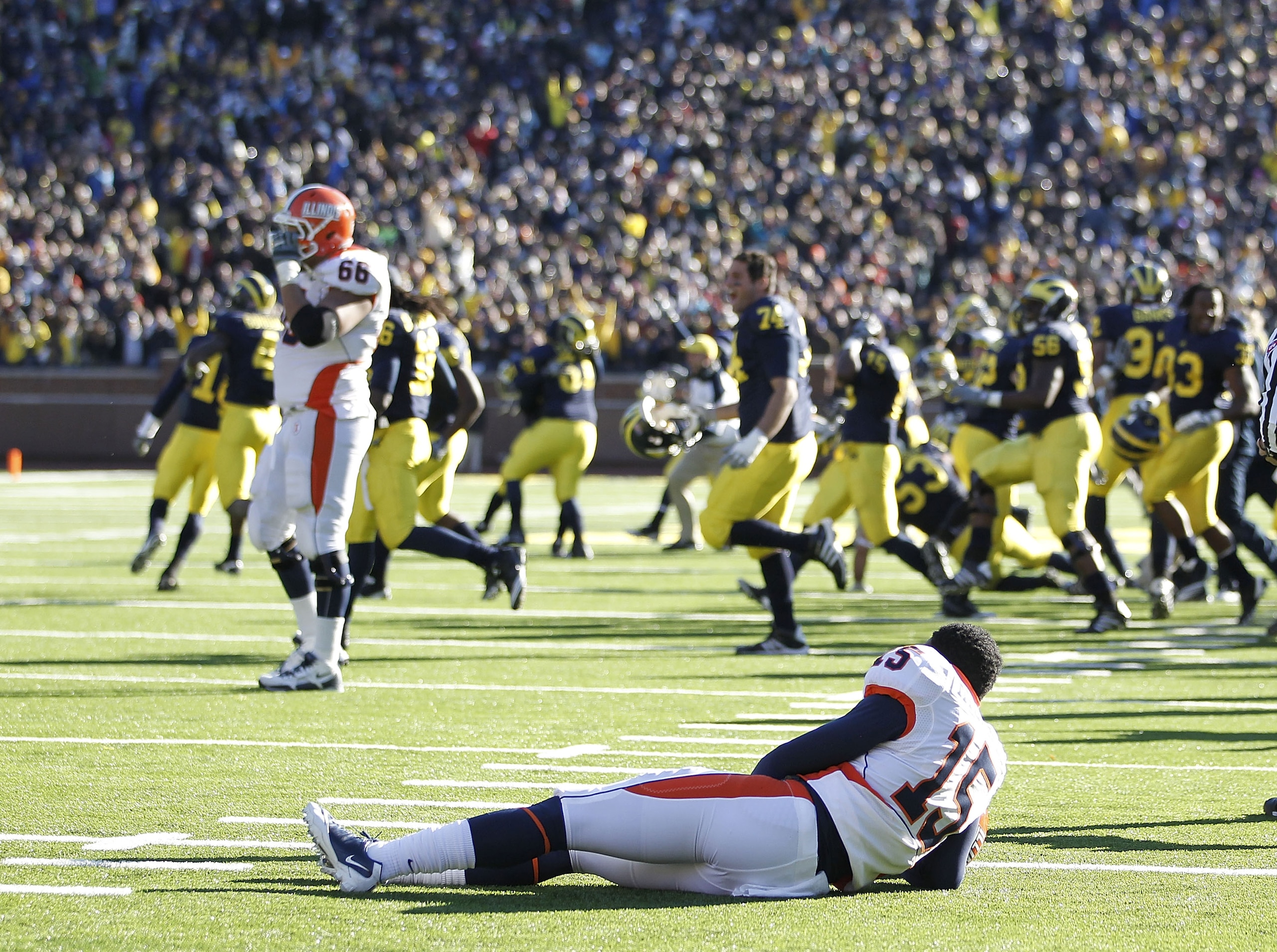 ANN ARBOR, MI - NOVEMBER 06:  Darius Millines #15 lays of the Illinios Fighting Illini lays on the ground as the Michigan Wolverines storm the field afer losing 65-67 in triple overtime at Michigan Stadium on November 6, 2010 in Ann Arbor, Michigan.  (Pho