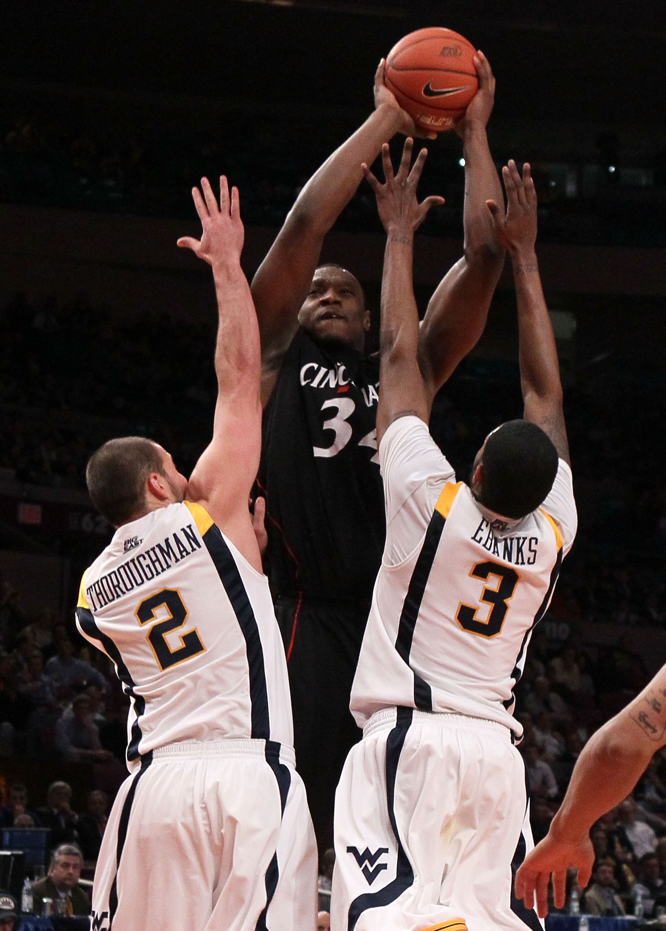 NEW YORK - MARCH 11:  Yancy Gates #34 of the Cincinnati Bearcats goes up with the ball against Cam Thoroughman #2 and Devin Ebanks #3 of the West Virginia Mountaineers during the quarterfinal of the 2010 NCAA Big East Tournament at Madison Square Garden o
