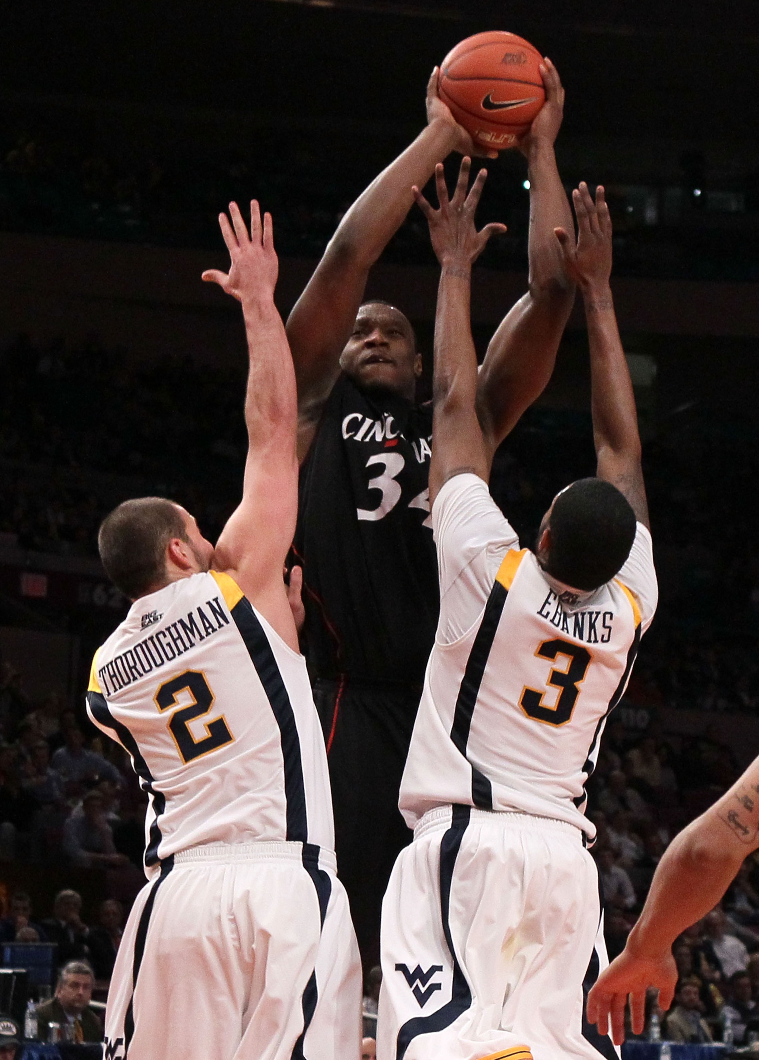NEW YORK - MARCH 11:  Yancy Gates #34 of the Cincinnati Bearcats goes up with the ball against Cam Thoroughman #2 and Devin Ebanks #3 of the West Virginia Mountaineers during the quarterfinal of the 2010 NCAA Big East Tournament at Madison Square Garden o