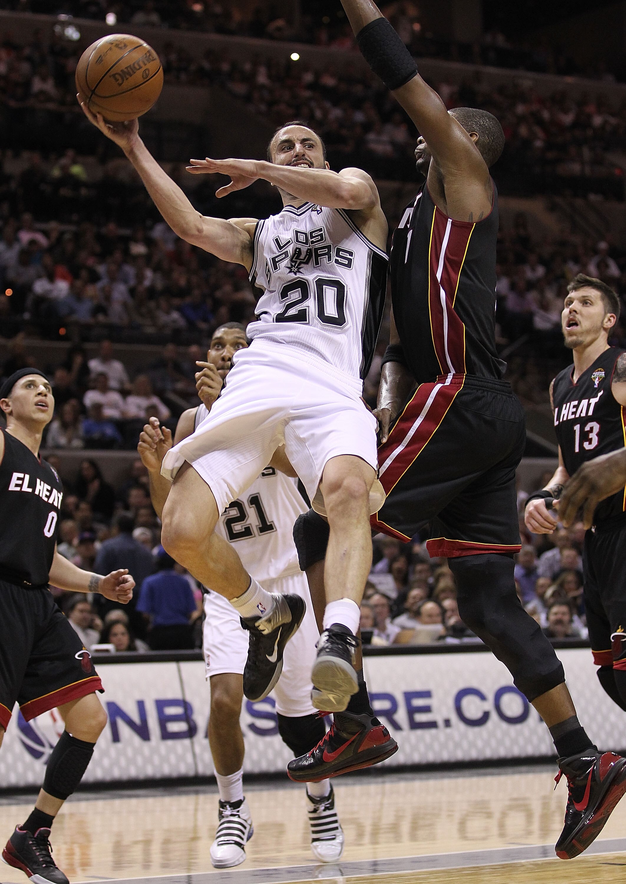 SAN ANTONIO, TX - MARCH 04:  Guard Manu Ginobili #20 of the San Antonio Spurs drives the lane against Chris Bosh #1 of the Miami Heat at AT&T Center on March 4, 2011 in San Antonio, Texas.   NOTE TO USER: User expressly acknowledges and agrees that, by do