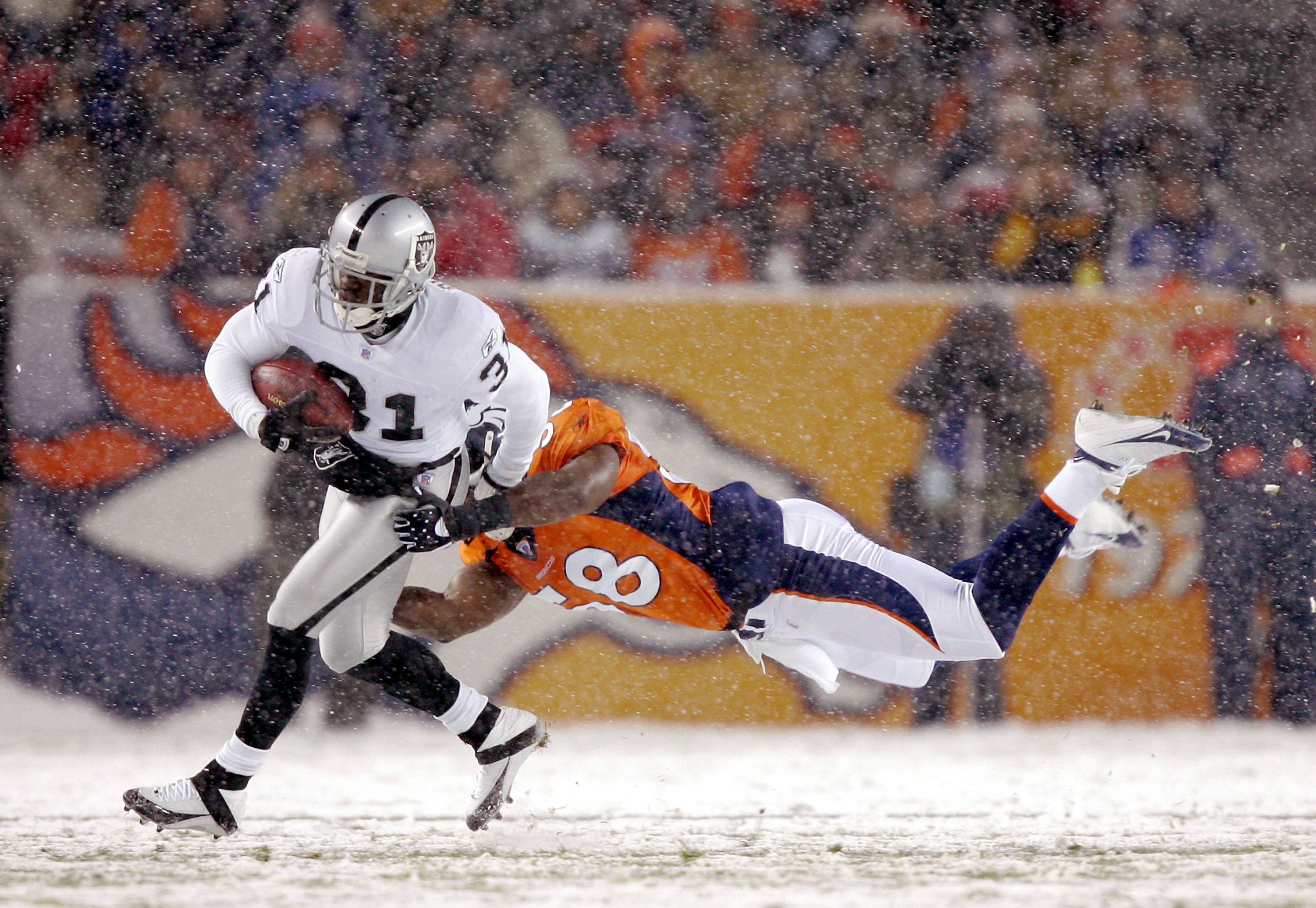 DENVER - NOVEMBER 28:  Linebacker Terry Pierce #58 of the Denver Broncos dives in an attempt to tackle punt returner Phillip Buchanon #31 of the Oakland Raiders on November 28, 2004 at Invesco Field at Mile High Stadium in Denver, Colorado. The Raiders wo