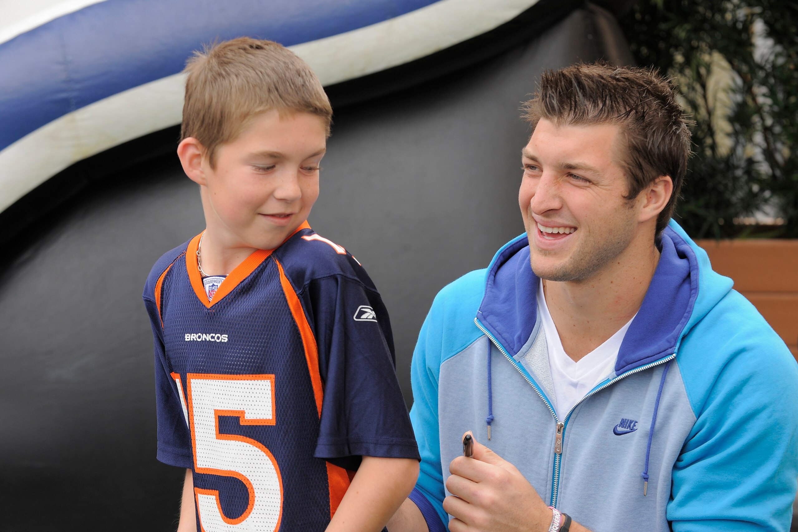 LAKE BUENA VISTA, FL - MAR 04: In this handout image provided by Disney Parks,  Denver Broncos quarterback Tim Tebow autographs a jersey for Cole Hoover, age 11, from Cape Coral, Florida at Disney's Hollywood Studios park in Lake Buena Vista, Florida on M