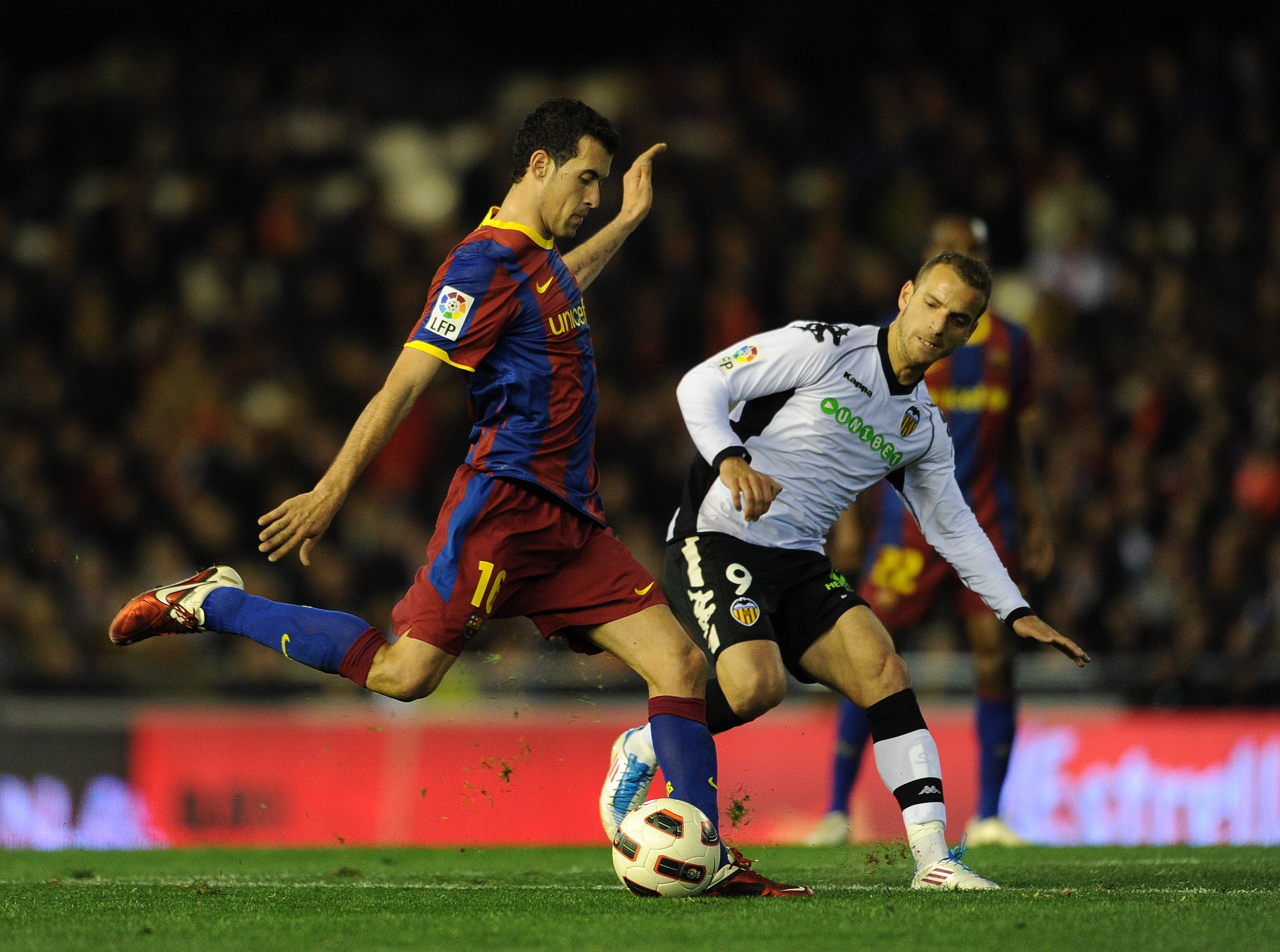 VALENCIA, SPAIN - MARCH 02:  Sergio Busquets (L) of Barcelona strikes the ball flanked by Roberto Soldado of Valencia during the la Liga match between Valencia and Barcelona at Estadio Mestalla on March 2, 2011 in Valencia, Spain.  (Photo by Jasper Juinen