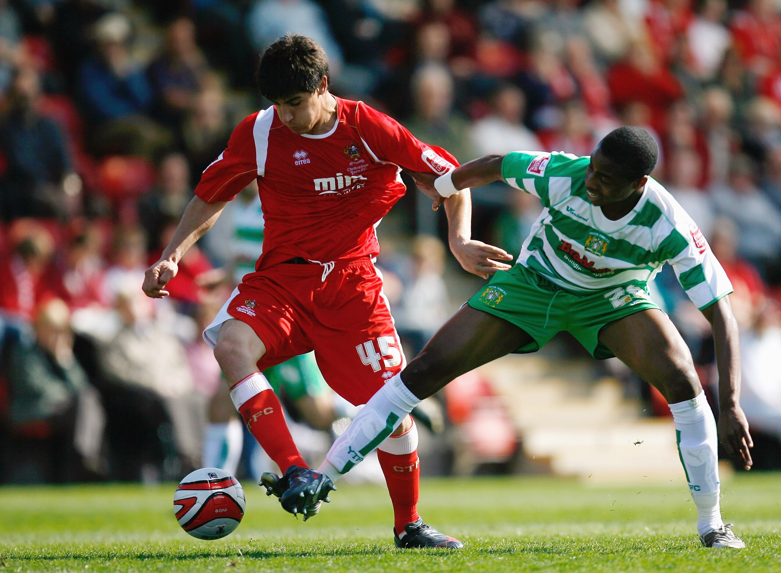 CHELTENHAM, UNITED KINGDOM - APRIL 13:  Jonathan Obika of Yeovil Town battles for the ball with Yuri Berchiche of Cheltenham Town during the Coca-Cola League One match between Cheltenham Town and Yeovil Town at Whaddon Road on April 13, 2009 in Cheltenham