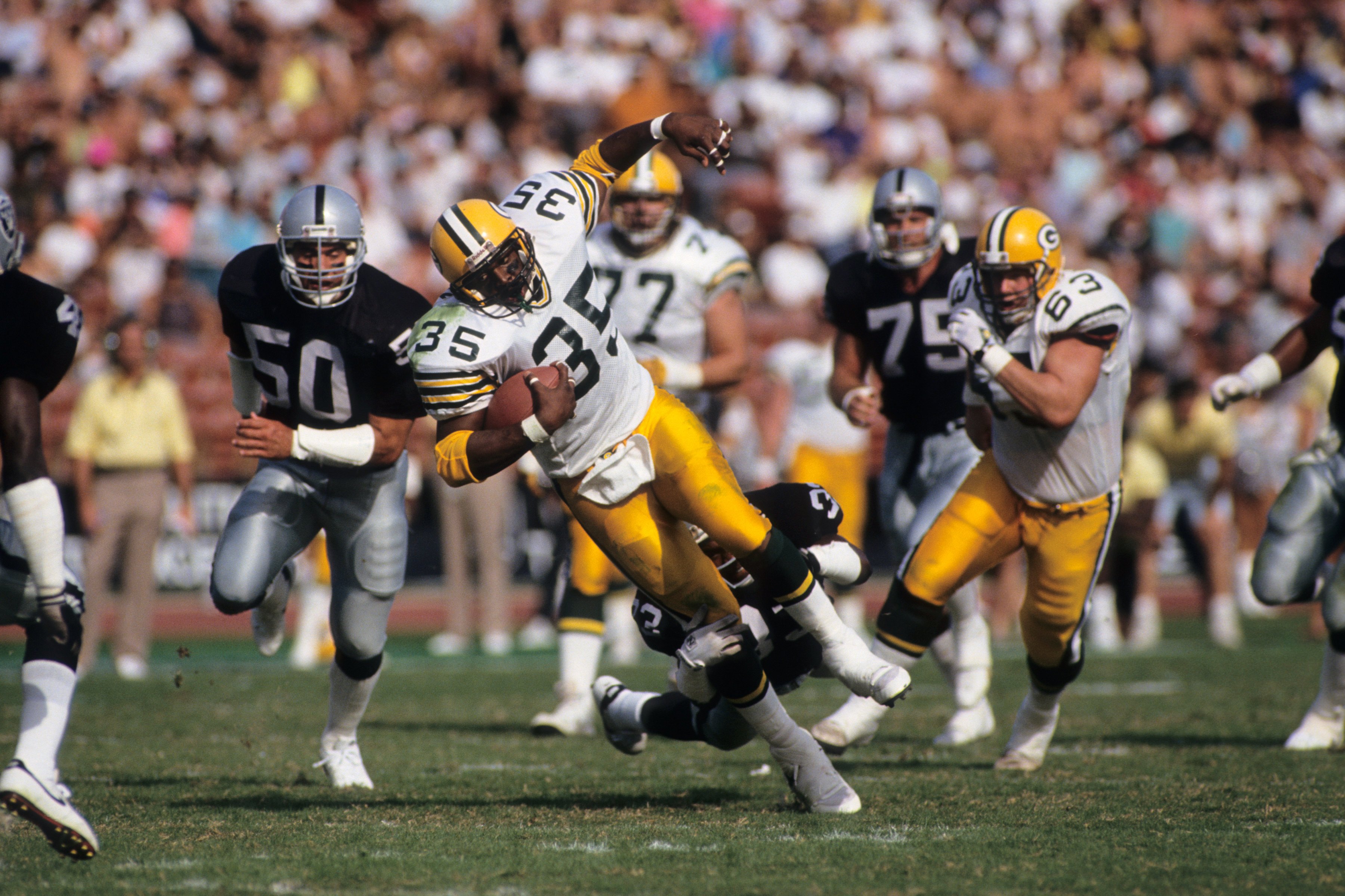 LOS ANGELES, CA - NOVEMBER 11:  Fullback Michael Haddix #35 of the Green Bay Packers is tackled by Eddie Anderson #35 of the Los Angeles Raiders during a game at the Los Angeles Memorial Coliseum on November 11, 1990 in Los Angeles, California.  The Packe