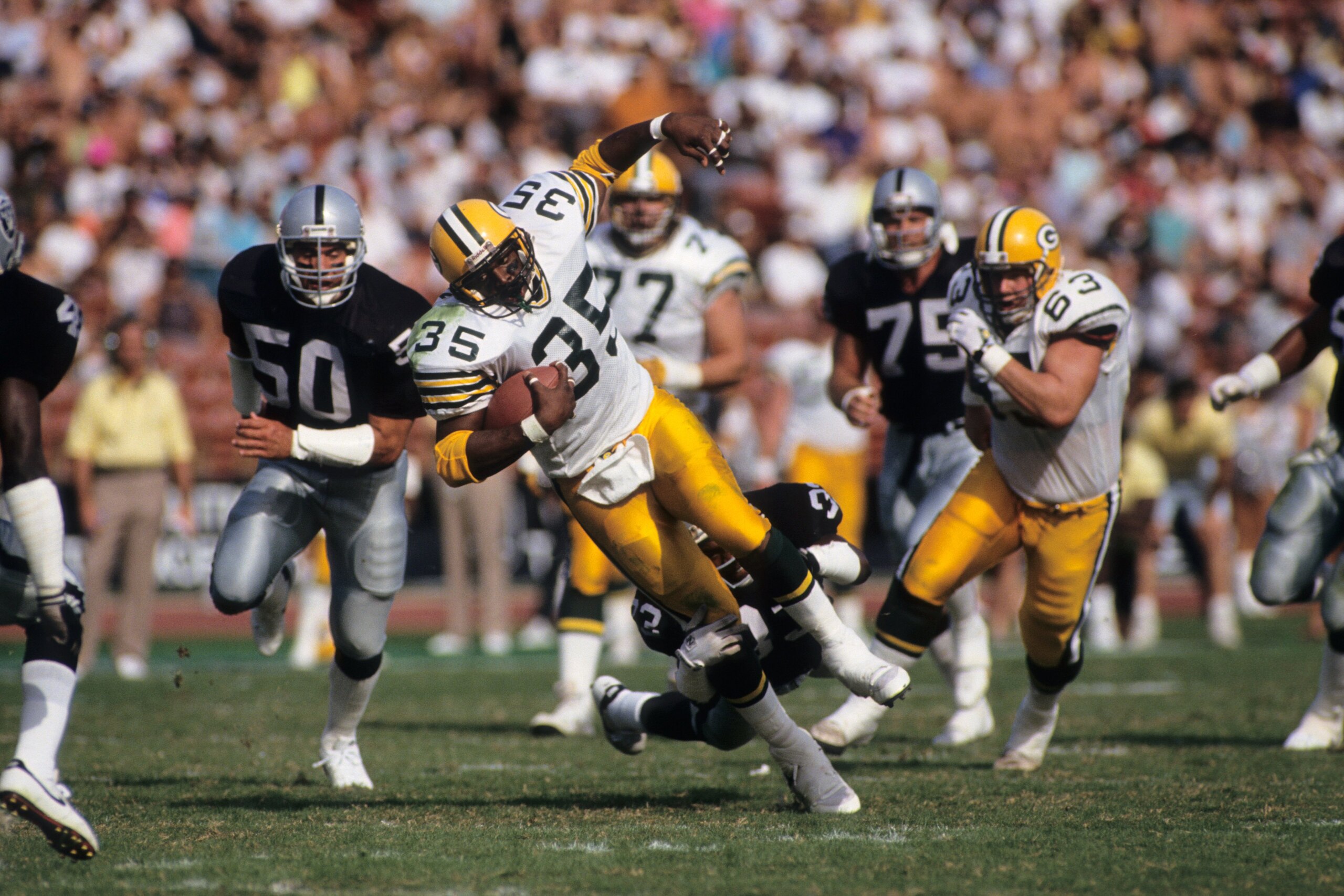LOS ANGELES, CA - NOVEMBER 11:  Fullback Michael Haddix #35 of the Green Bay Packers is tackled by Eddie Anderson #35 of the Los Angeles Raiders during a game at the Los Angeles Memorial Coliseum on November 11, 1990 in Los Angeles, California.  The Packe