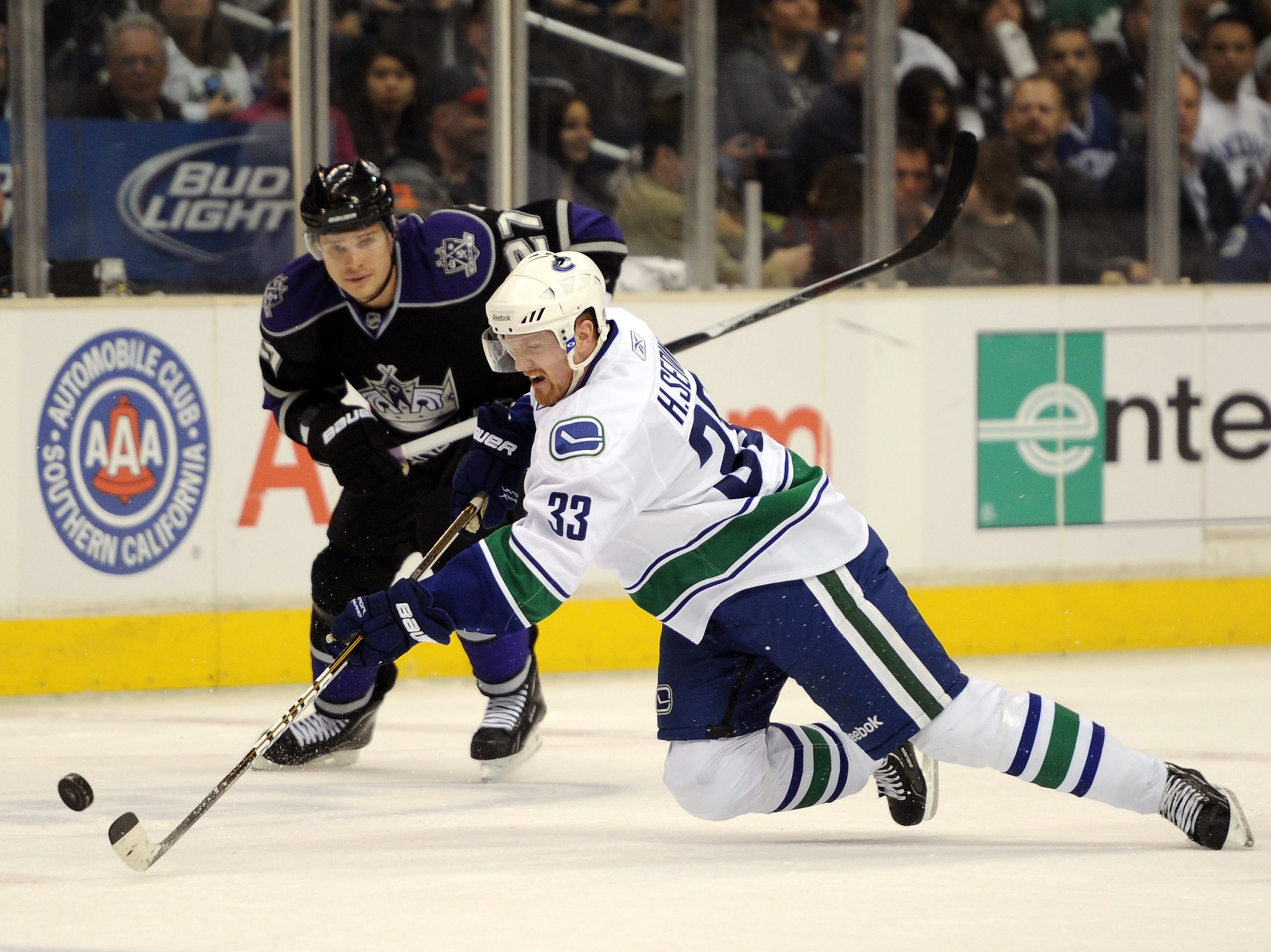 LOS ANGELES, CA - MARCH 05:  Henrik Sedin #33 of the Vancouver Canucks falls as he plays the puck in front of Alexei Ponikarovsky #27 of the Los Angeles Kings during the first period at the Staples Center on March 5, 2011 in Los Angeles, California.  (Pho